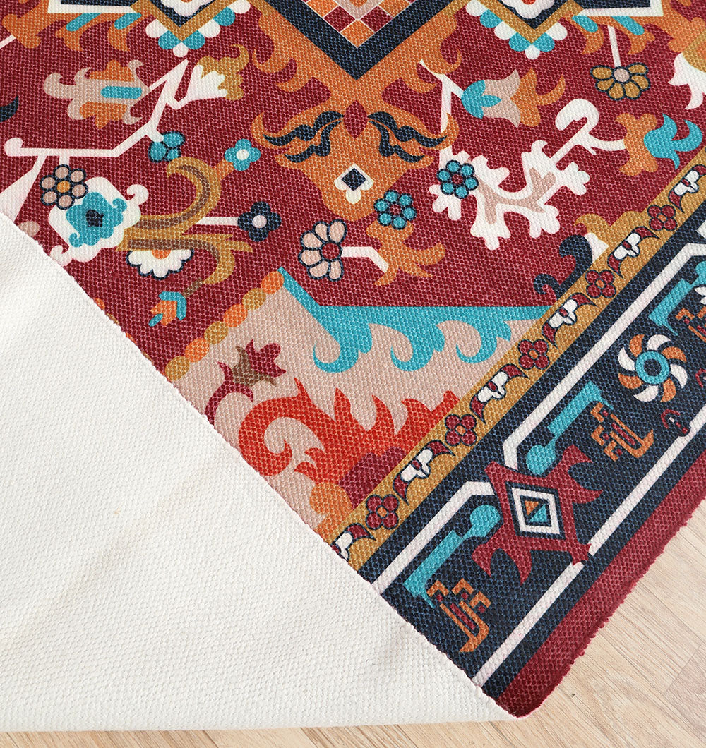 The RAMSHA HOME Bohemian Floral Medallion Printed Area Rug DD-050 features vibrant red, blue, orange, and white geometric and floral patterns, displayed partially folded to show its plain white underside on a light wooden floor.