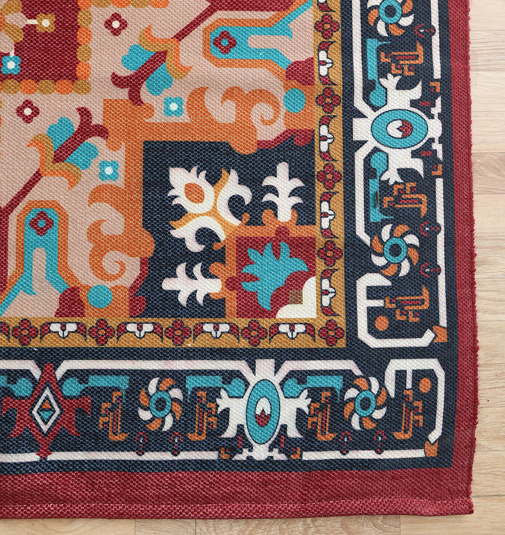 A close-up of the RAMSHA HOME Bohemian Floral Medallion Printed Area Rug DD-050, featuring vibrant geometric and floral designs in red, orange, blue, gold, white, and black on a light wooden floor.
