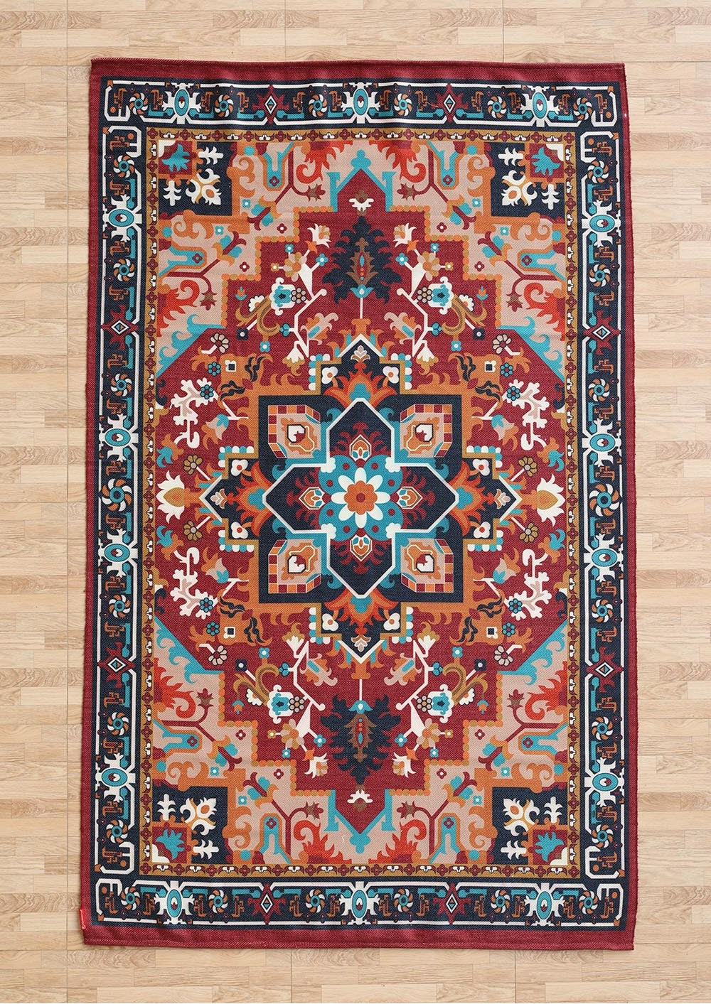 The RAMSHA HOME Bohemian Floral Medallion Printed Area Rug DD-050, featuring vibrant geometric and floral designs in red, blue, white, gold, and teal, is displayed on a light wooden floor.