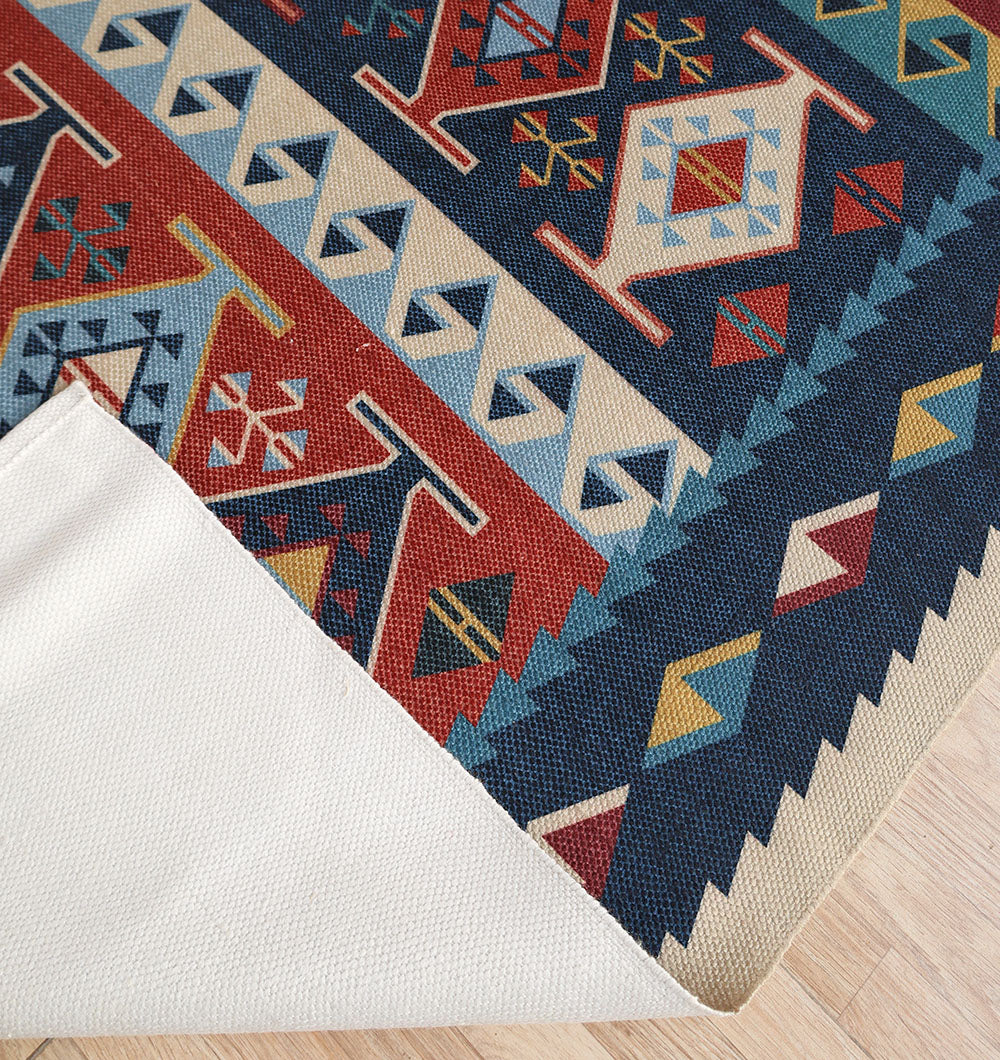 The RAMSHA HOME Classic Heritage 145x240 cm Digital Printed Area Rug DD-051, featuring colorful geometric patterns, is shown partially lifted at the corner to display a white non-slip rug pad on a light wooden floor.
