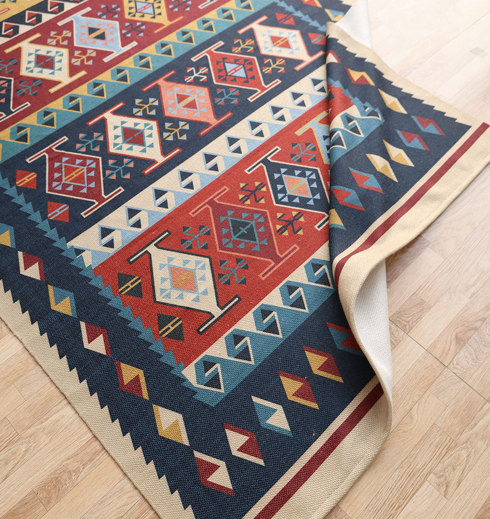 The RAMSHA HOME Classic Heritage 145x240 cm Digital Printed Area Rug DD-051, featuring Persian-inspired geometric patterns in red, blue, yellow, and cream with diamond and zigzag motifs, is partially folded on a light wooden floor.