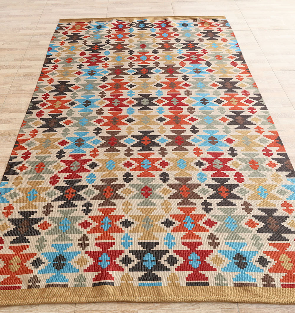 The RAMSHA HOME Tribal Mosaic Digital Printed Rug 145x240 cm DD-052 features a geometric, tribal pattern in red, blue, black, beige, and gold with repeating diamond and cross designs, shown laid on a light wooden floor.