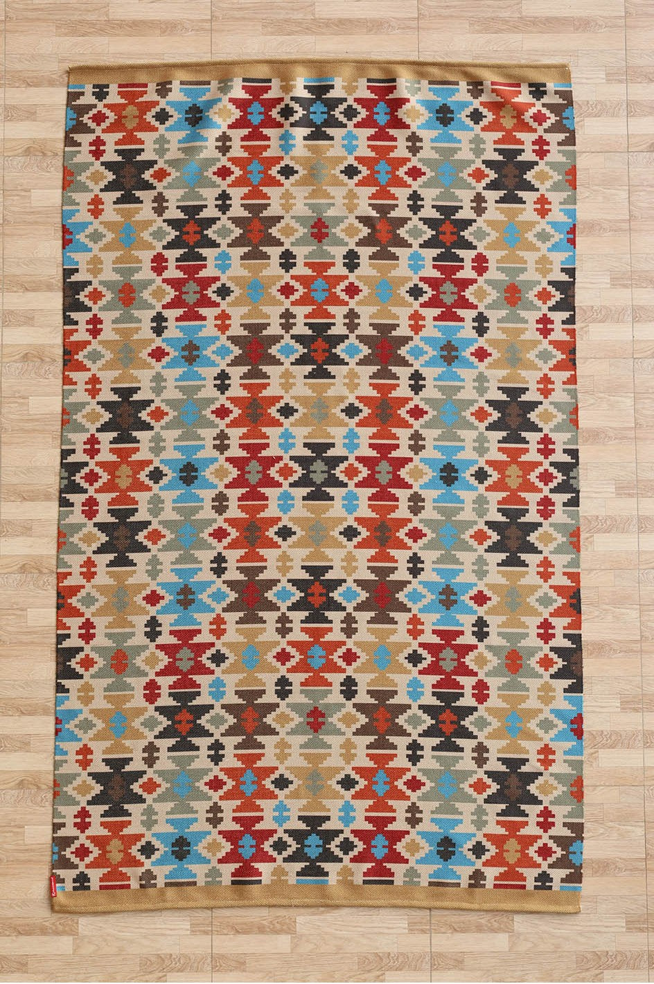 The RAMSHA HOME Tribal Mosaic Digital Printed Rug 145x240 cm (DD-052) features a vibrant, traditional Kilim-inspired geometric pattern in red, blue, beige, black, and brown with diamond and zigzag shapes on a light wood floor.