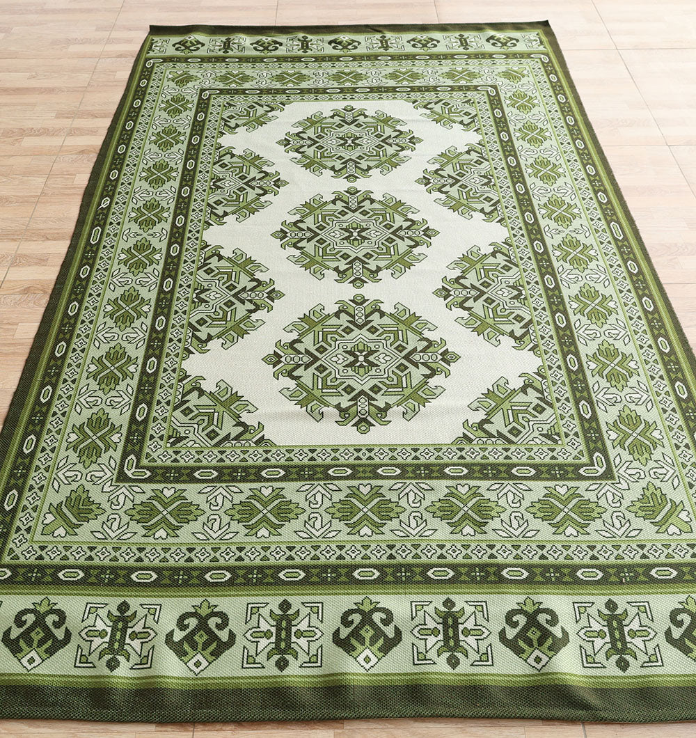The RAMSHA HOME Contemporary Tribal Digital Print Rug (145x240 cm, DD-053) features intricate geometric and floral patterns in green and cream, decorative borders, and symmetrical central motifs, shown laid flat on a light wood floor.