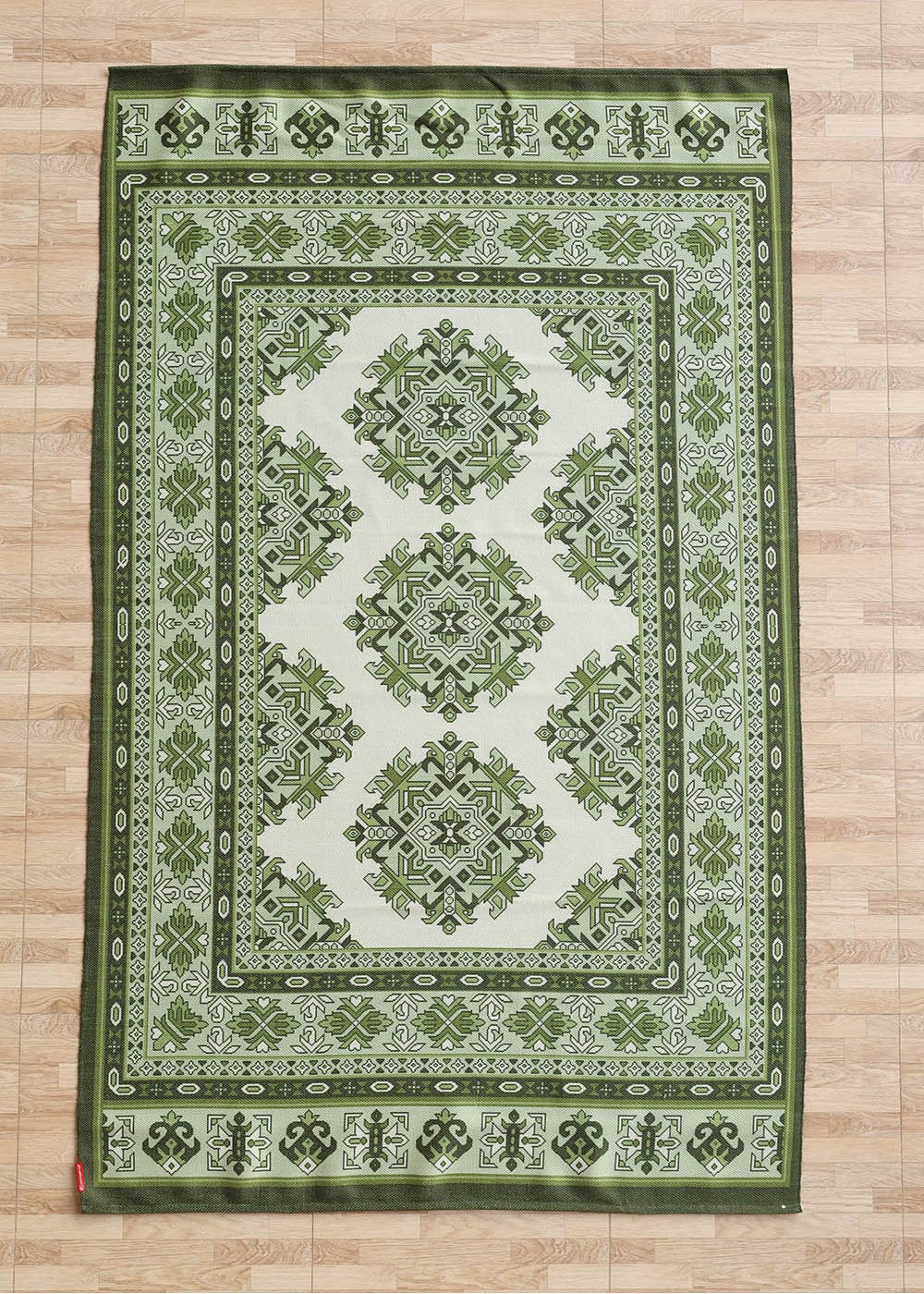 A rectangular green and white RAMSHA HOME Contemporary Tribal Digital Print Rug (145x240 cm, DD-053) with intricate geometric and floral motifs lies on a light wood floor, its design echoing symmetrical patterns within multiple decorative borders.