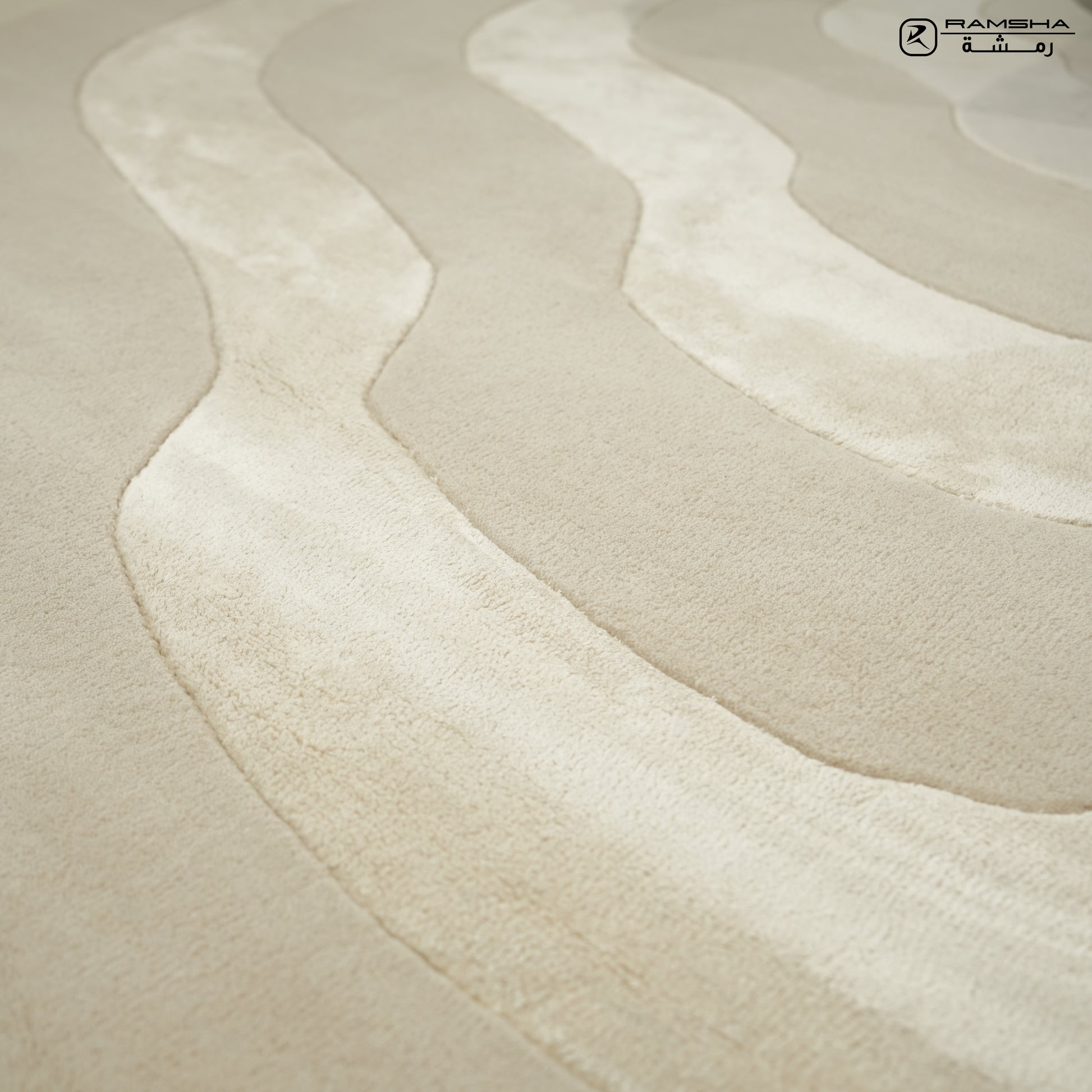 Close-up of the RAMSHA HOME Wool & Tencel Multi Color Rug HTWV-91, showing its beige base with wavy, raised cream and light beige textures. A small logo with text appears in the upper right corner.