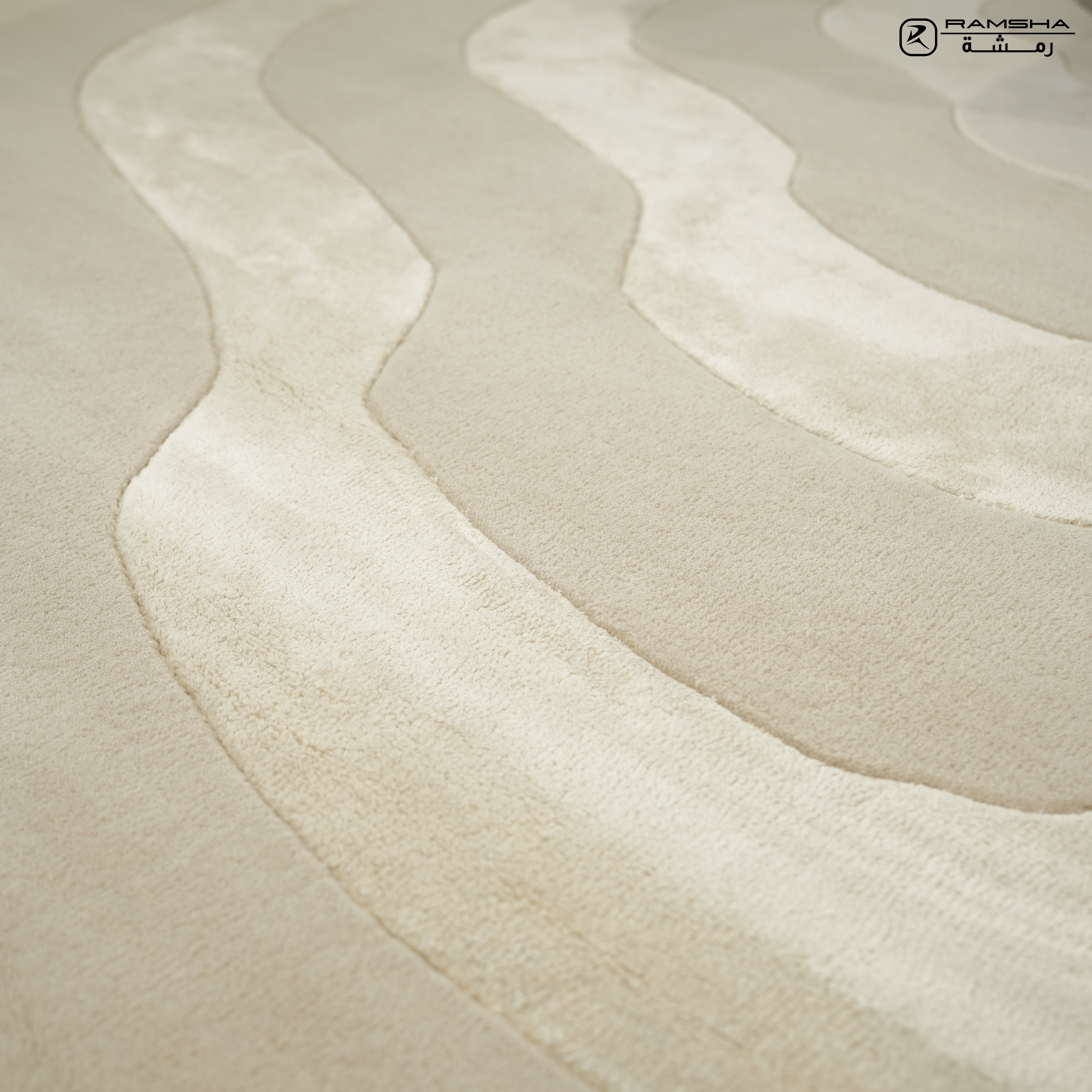Close-up of the RAMSHA HOME Wool & Tencel Multi Color Rug HTWV-91, showing its beige base with wavy, raised cream and light beige textures. A small logo with text appears in the upper right corner.