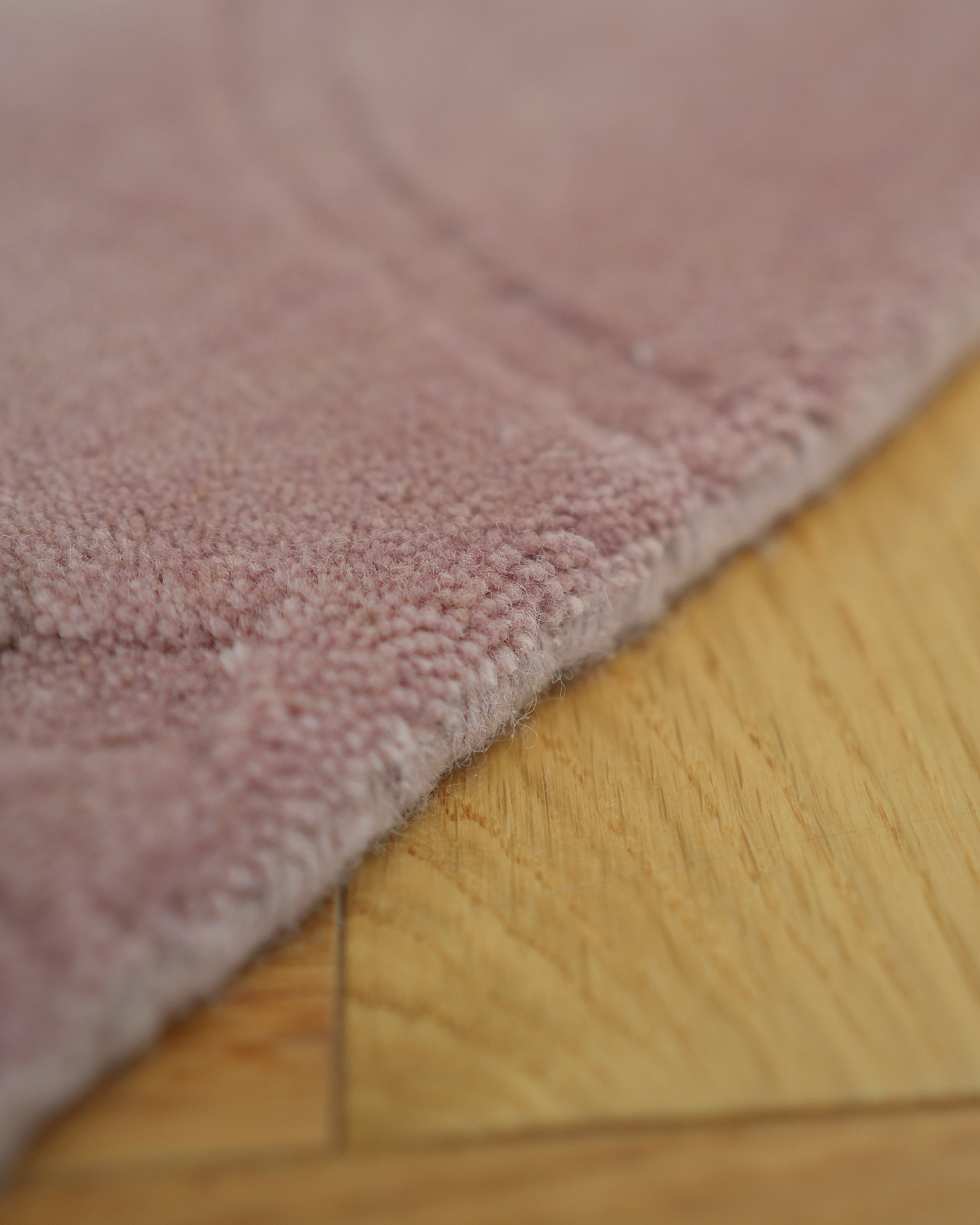 Close-up of the RAMSHA HOME Rectangle Handmade Pink Color Area Rug (LKH-029) on a light wooden floor, showing its soft texture, visible fibers, wood grain, and a seam between floorboards.