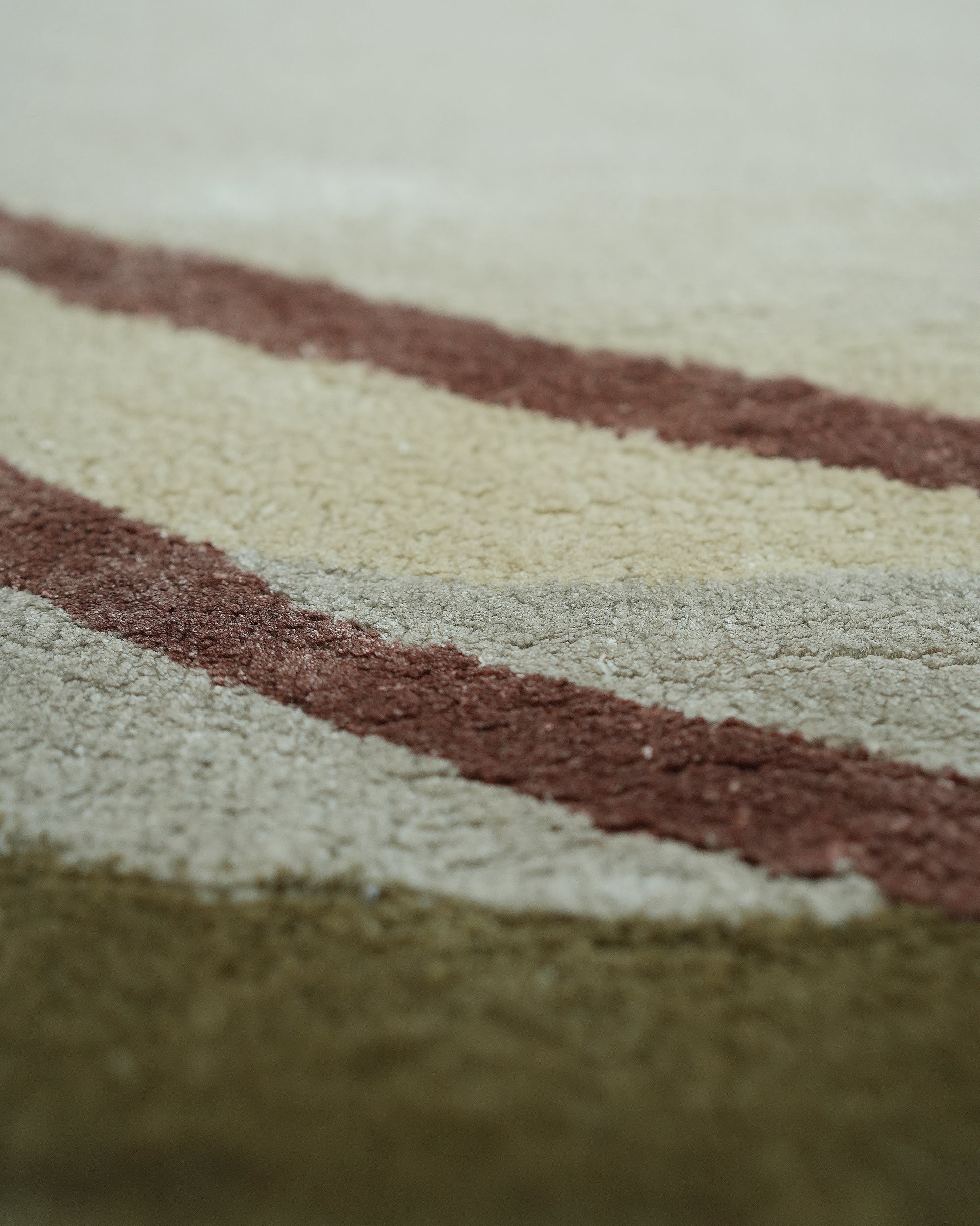 Close-up of the RAMSHA HOME Handmade Hand-Tufted Carpet HTWV-60, showcasing its textured surface with diagonal wavy stripes in beige, brown, and olive green.