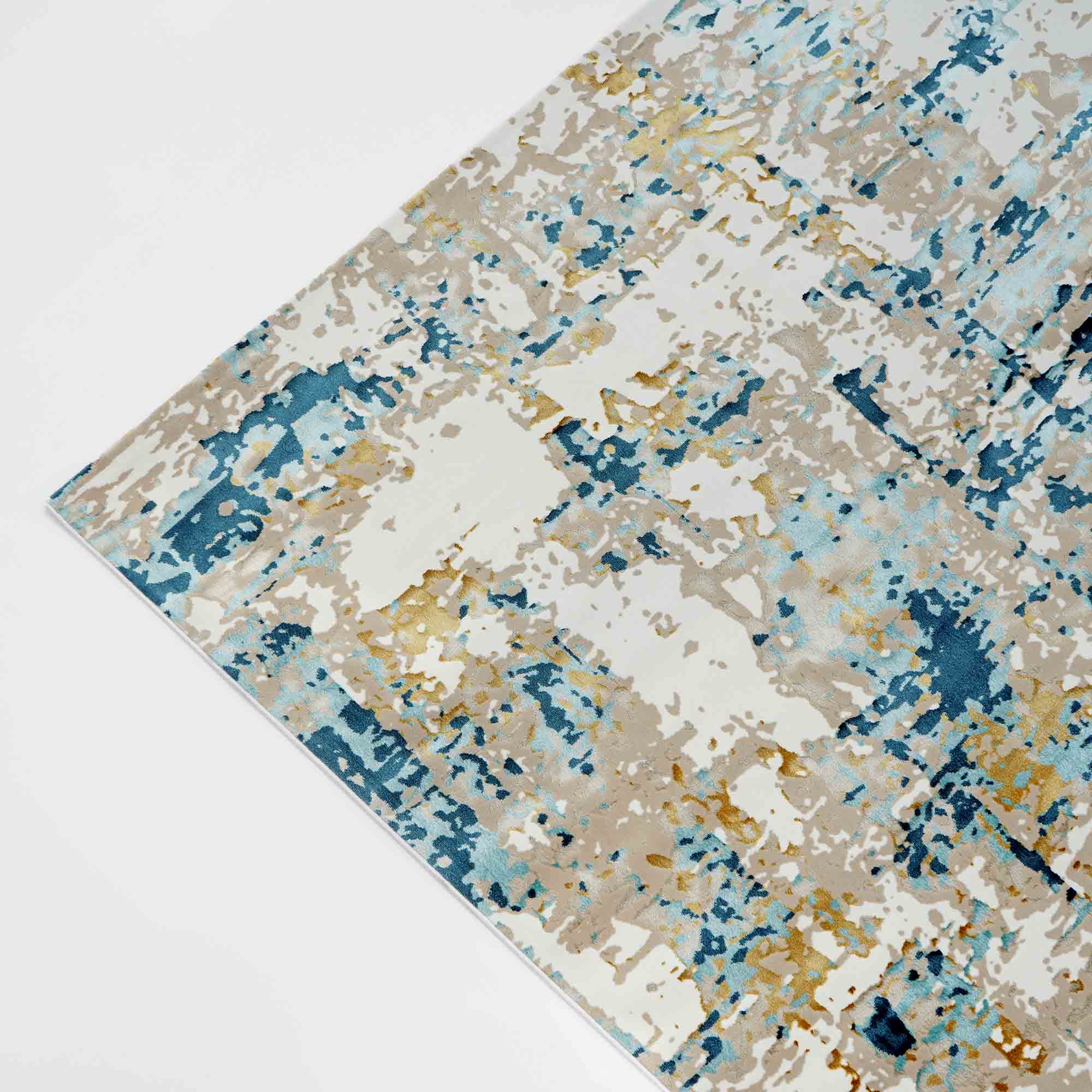 A close-up, angled view of the RAMSHA HOME Stunning Cream & Blue Turkish Machine Made Rug for Bedroom (MZ61B), featuring abstract Persian patterns in blue, beige, white, and gold on a white background.