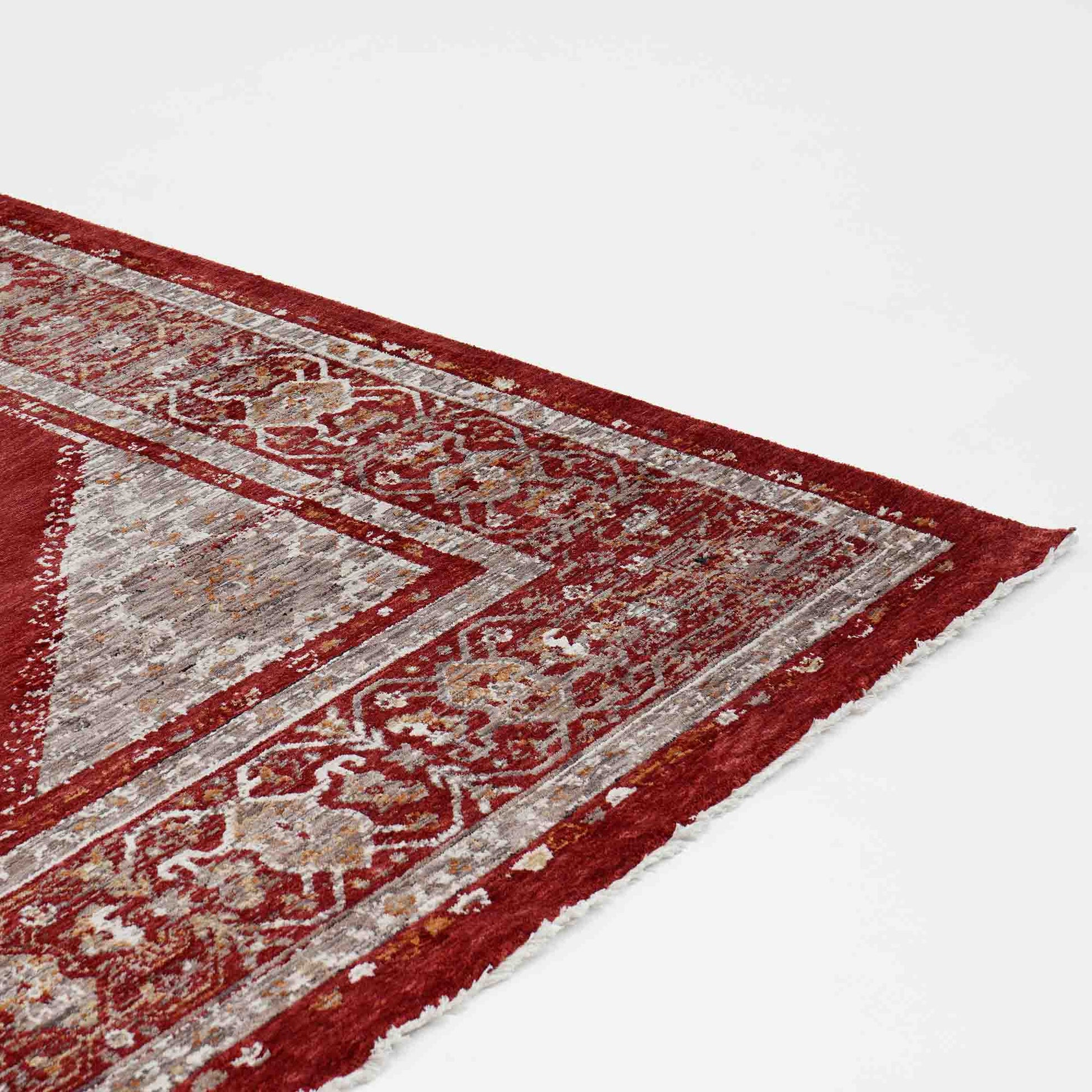 A close-up of the Luxurious Texture Turkey Multi Color Machine Made Rug - K643C by RAMSHA HOME shows its intricate geometric and floral patterns in red and beige, with slightly frayed edges, set against a plain white background.