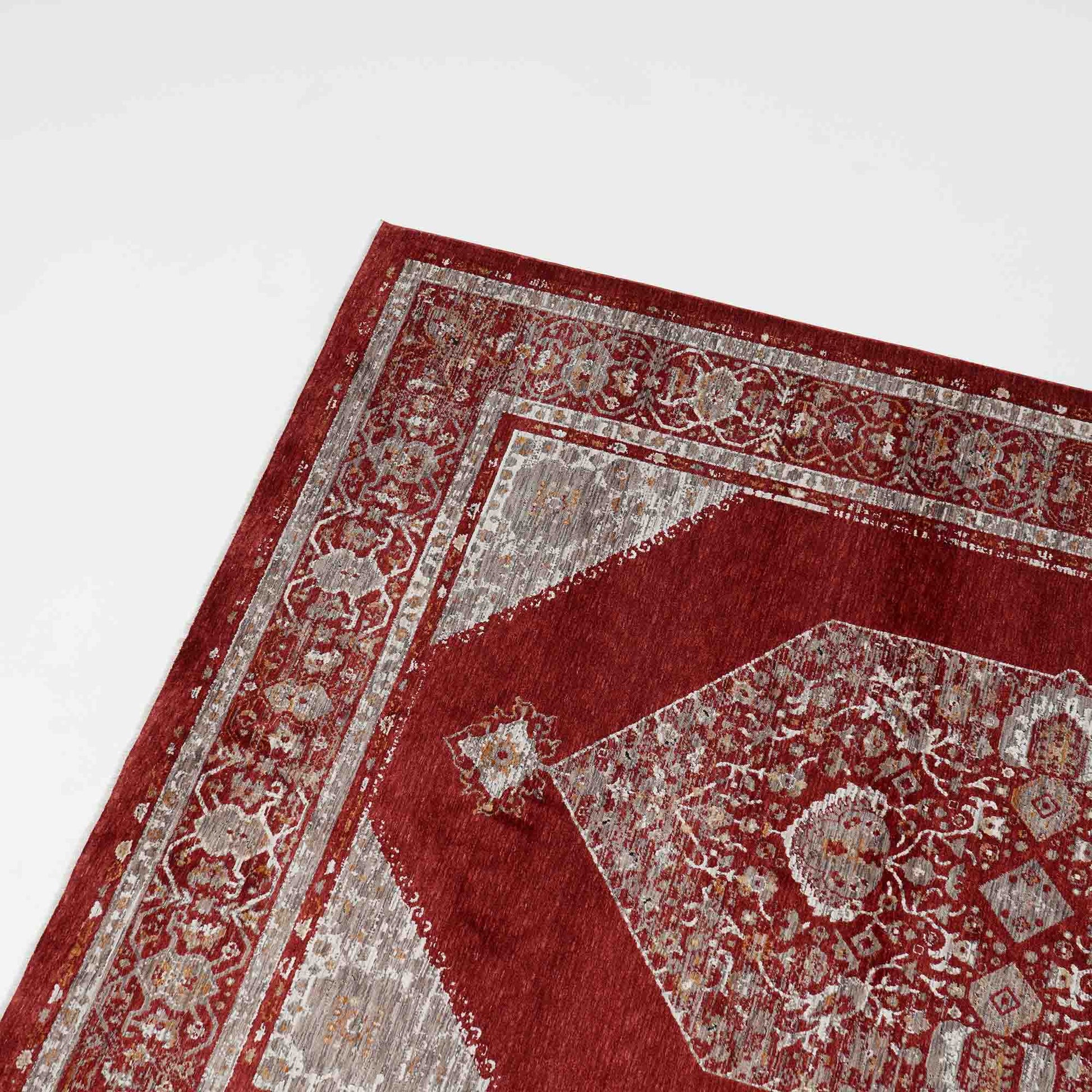 Close-up of the corner of the Luxurious Texture Turkey Multi Color Machine Made Rug - K643C by RAMSHA HOME, showcasing intricate red and gray floral and geometric designs on a white background.