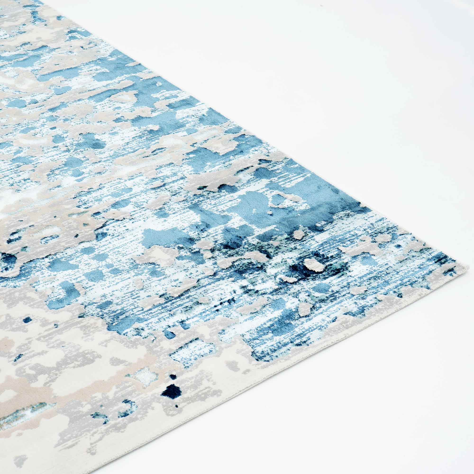 A close-up of the RAMSHA HOME Light Blue Turkey Area Rug NF98B highlights its textured, abstract painterly patterns in blue, gray, and white tones on a light background.