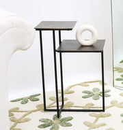 The RAMSHA HOME Modern Dual-Tier Side Tables (GH-075-A) feature antique brass tops and black iron bases, paired beside a white sofa on a patterned rug, with a circular-cutout white vase adding modern style.