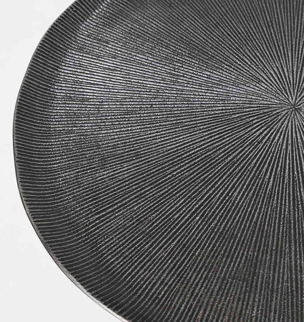 Close-up of the RAMSHA HOME Modern Black Metal Side Table, featuring a textured round top with radiating grooves and a pyramid base. The table is partially shown against a white background.