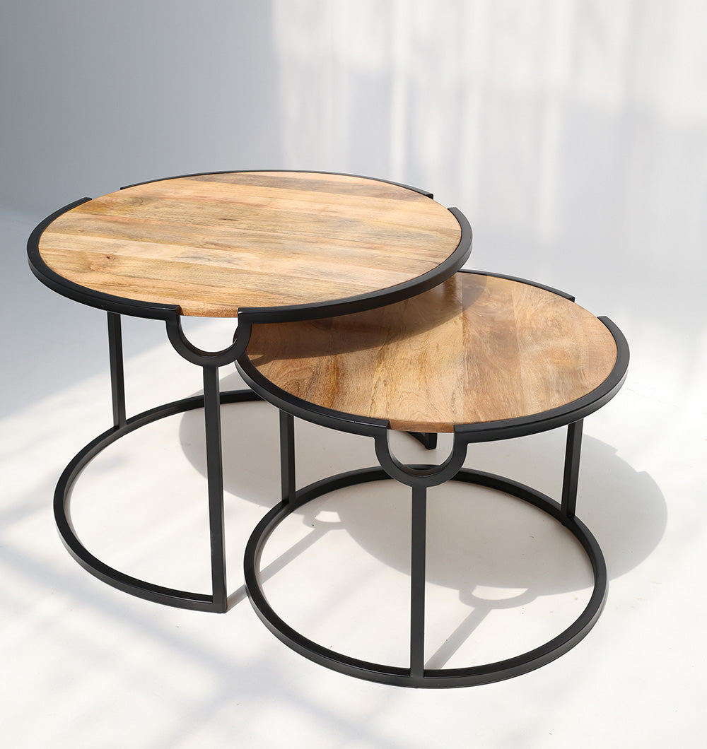 The RAMSHA HOME Modern Nesting Coffee Table Set (GH-094) features two round wooden top tables with black metal frames, the smaller partially tucked under the larger, both placed on a white floor and casting soft shadows.