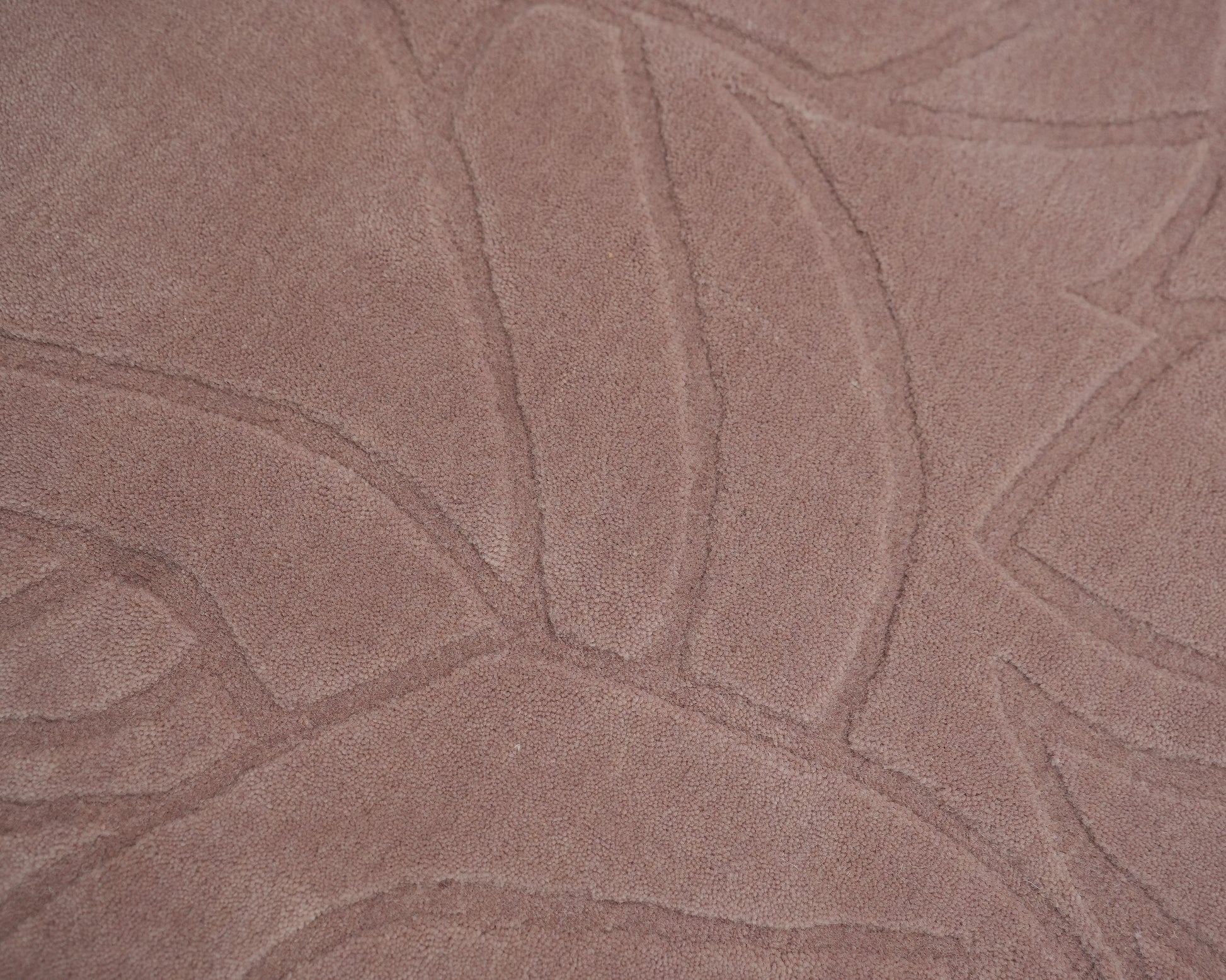 Close-up of the RAMSHA HOME Rectangle Handmade Pink Color Area Rug (LKH-029), featuring a textured dusty pink surface and raised abstract curved lines in a carved floral or leaf-like pattern.