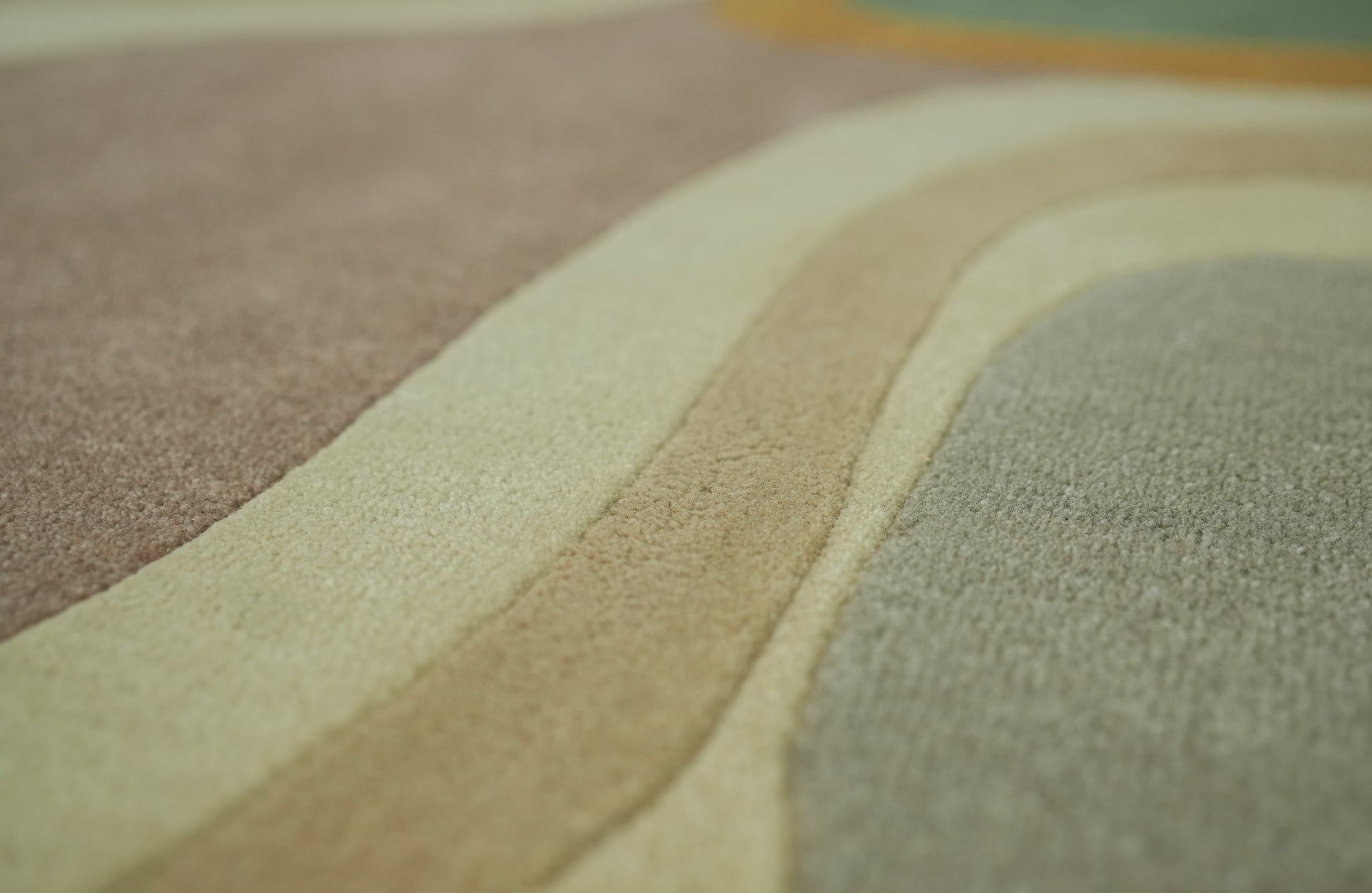 Close-up of the RAMSHA HOME Handmade Multicolor Shaped Area Rug HTW 127 (200cm), featuring wavy, overlapping stripes in beige, brown, cream, and muted green for a soft, retro-inspired textured look.
