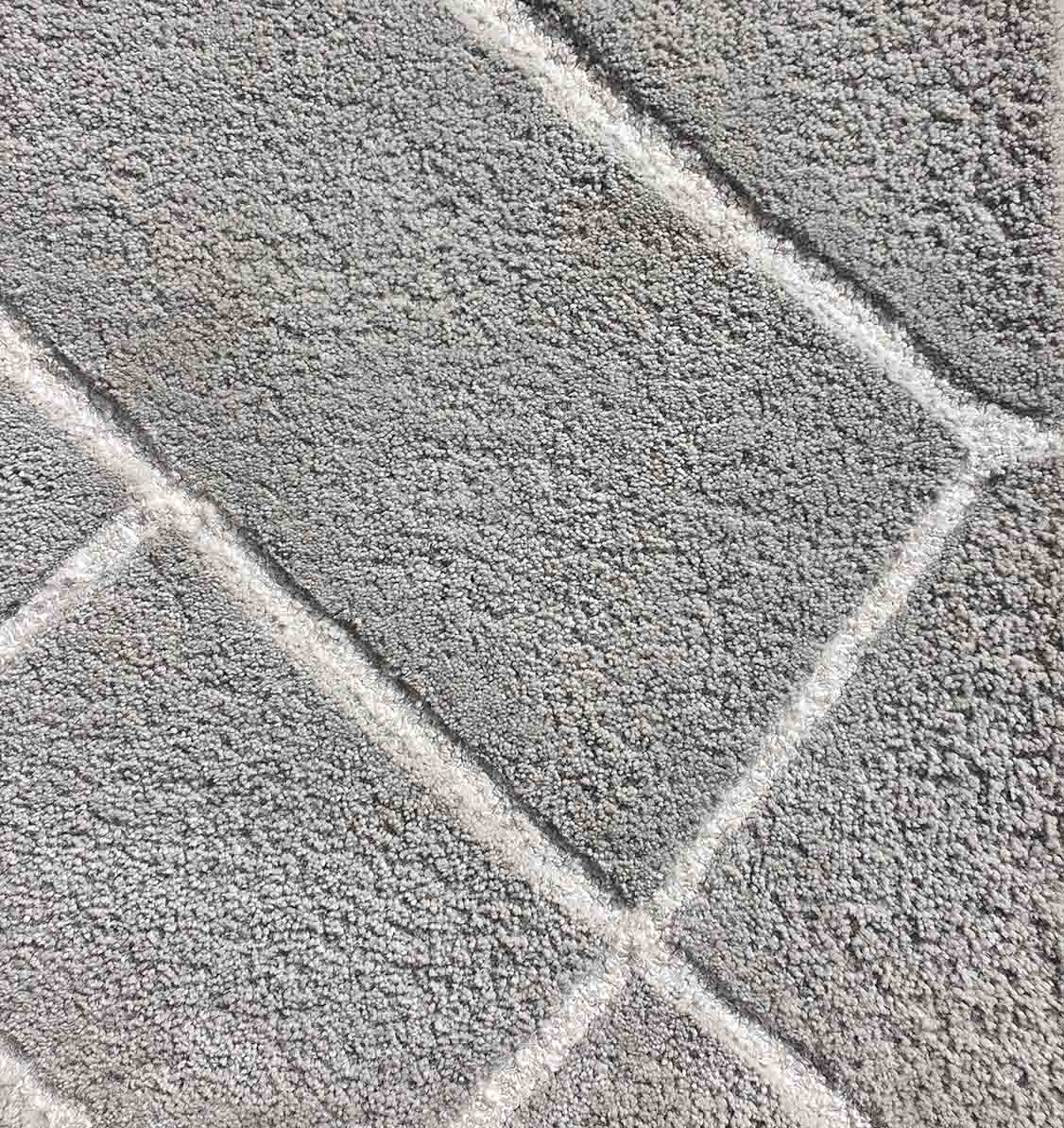 Close-up of the RAMSHA HOME Luxurious Handmade Rug - HTP 12 (300x400cm), showcasing textured gray rectangular patterns and lighter lines in a geometric arrangement, reminiscent of stone blocks.