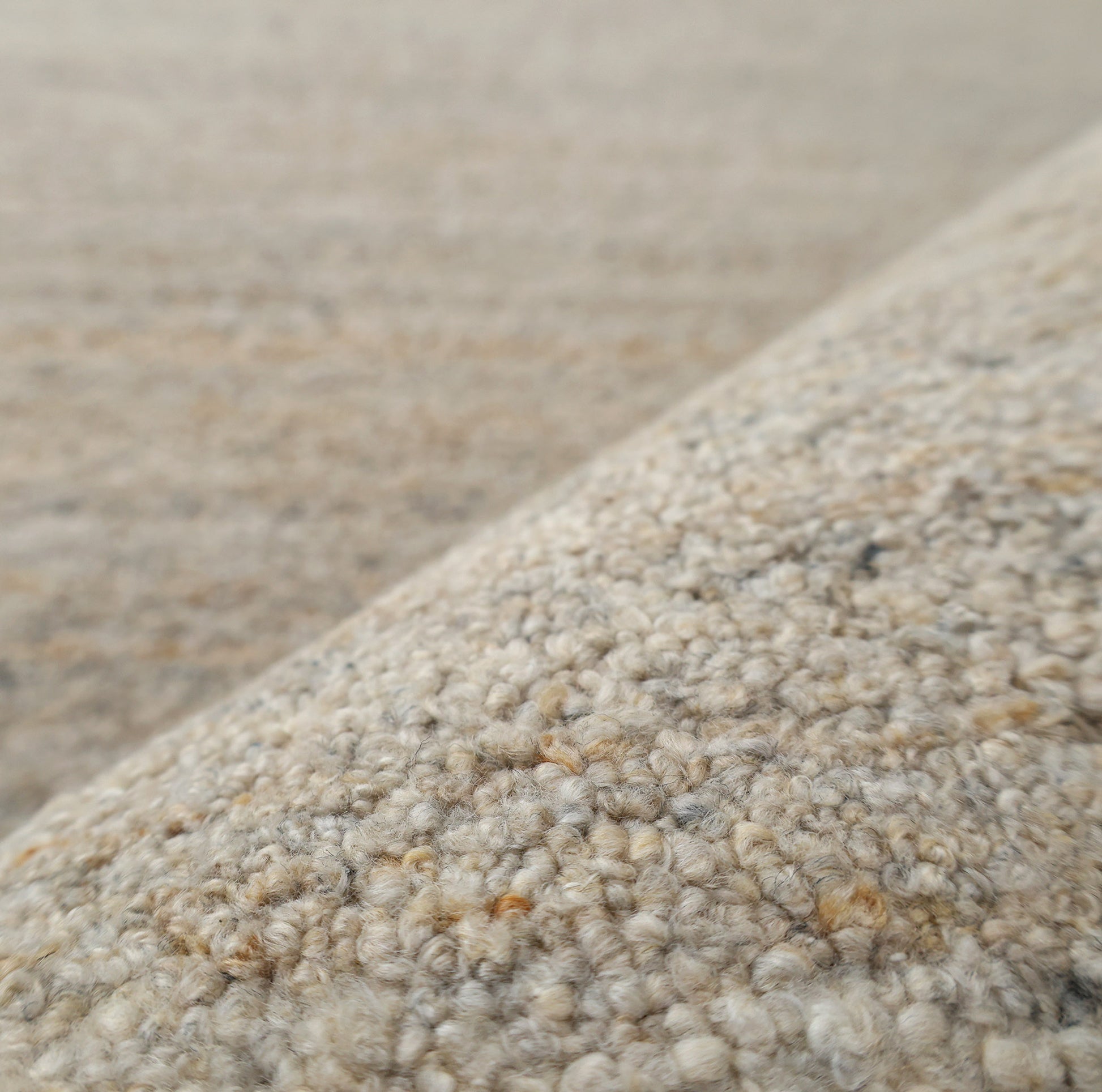 Close-up of the RAMSHA HOME Handmade Natural Wool Rug – Textured Beige Area Rug- HTP 25, featuring handwoven looped fibers and detailed patterns. The neutral beige texture stands out in the foreground with a softly blurred background.