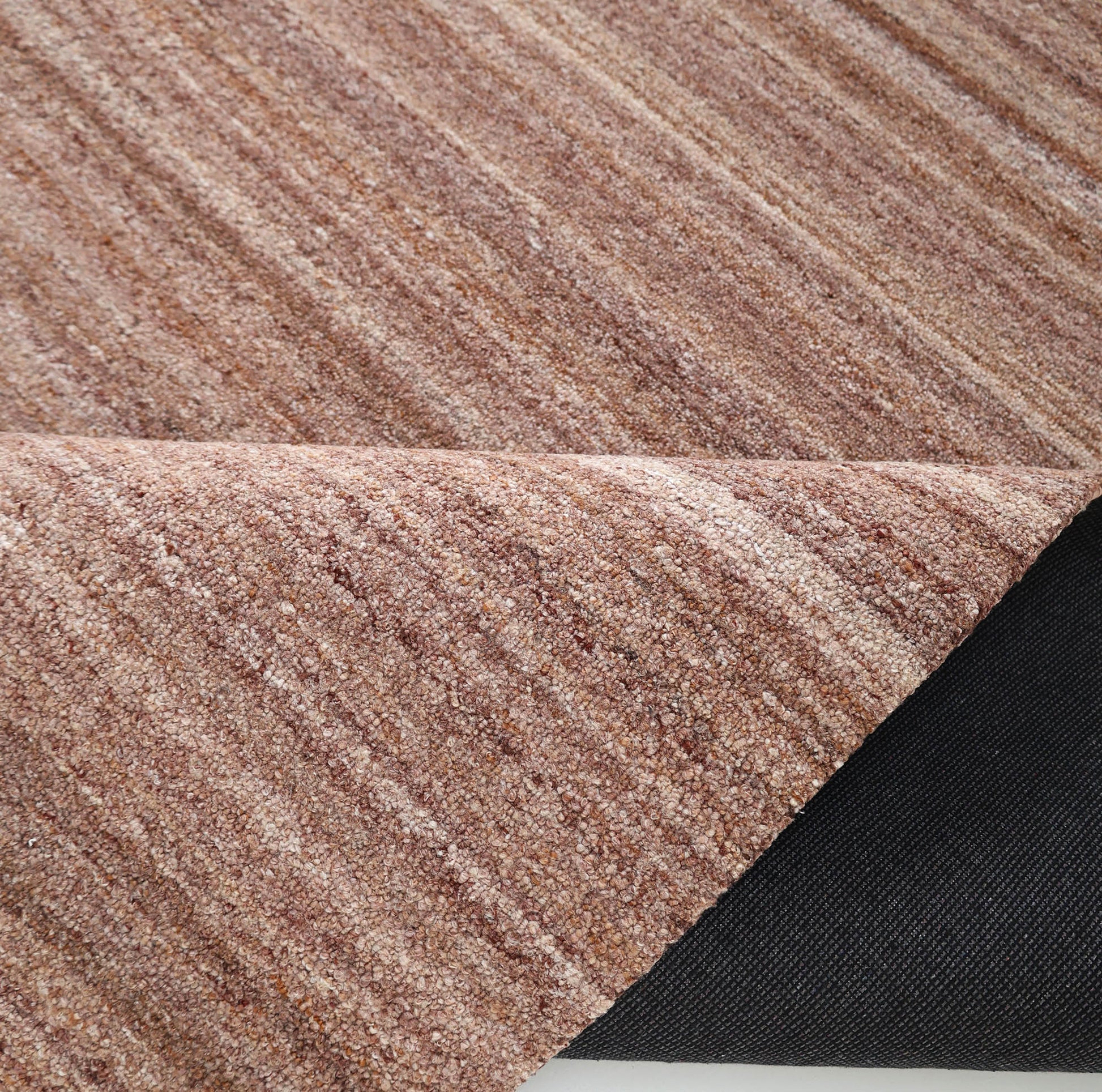 A close-up of RAMSHA HOME's Handmade Wool Rug – Textured Beige Area Rug (HTP 26), featuring subtle stripes, with one corner flipped to display the black non-slip backing underneath.