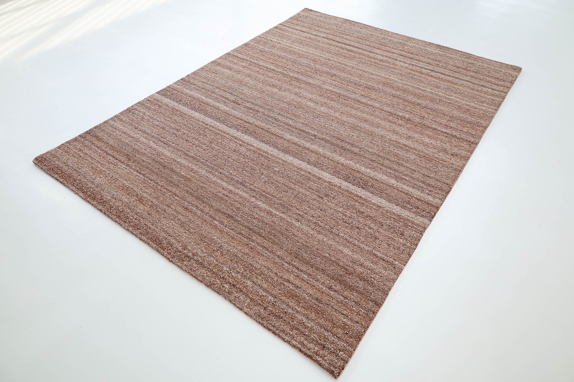 The RAMSHA HOME Handmade Wool Rug – Textured Beige Area Rug- HTP 26 features a rectangular, flat-woven design with subtle brown and beige stripes, displayed on a white floor.