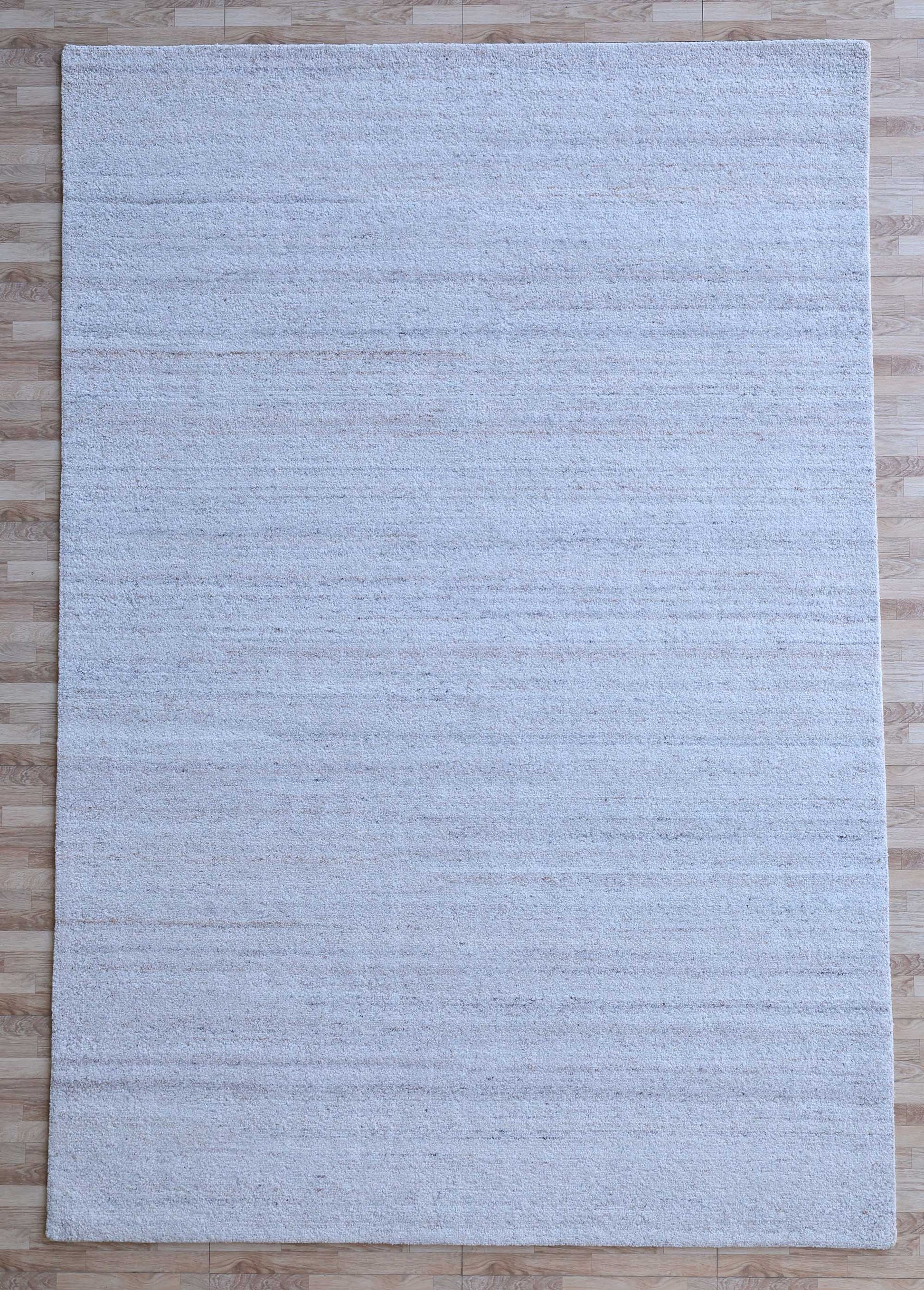 The RAMSHA HOME Natural Ivory Handmade Wool Rug – Modern Luxury Area Rug HTP 28, a large rectangular piece with subtle horizontal patterns and minimalist design, is shown on a light wood floor from above.