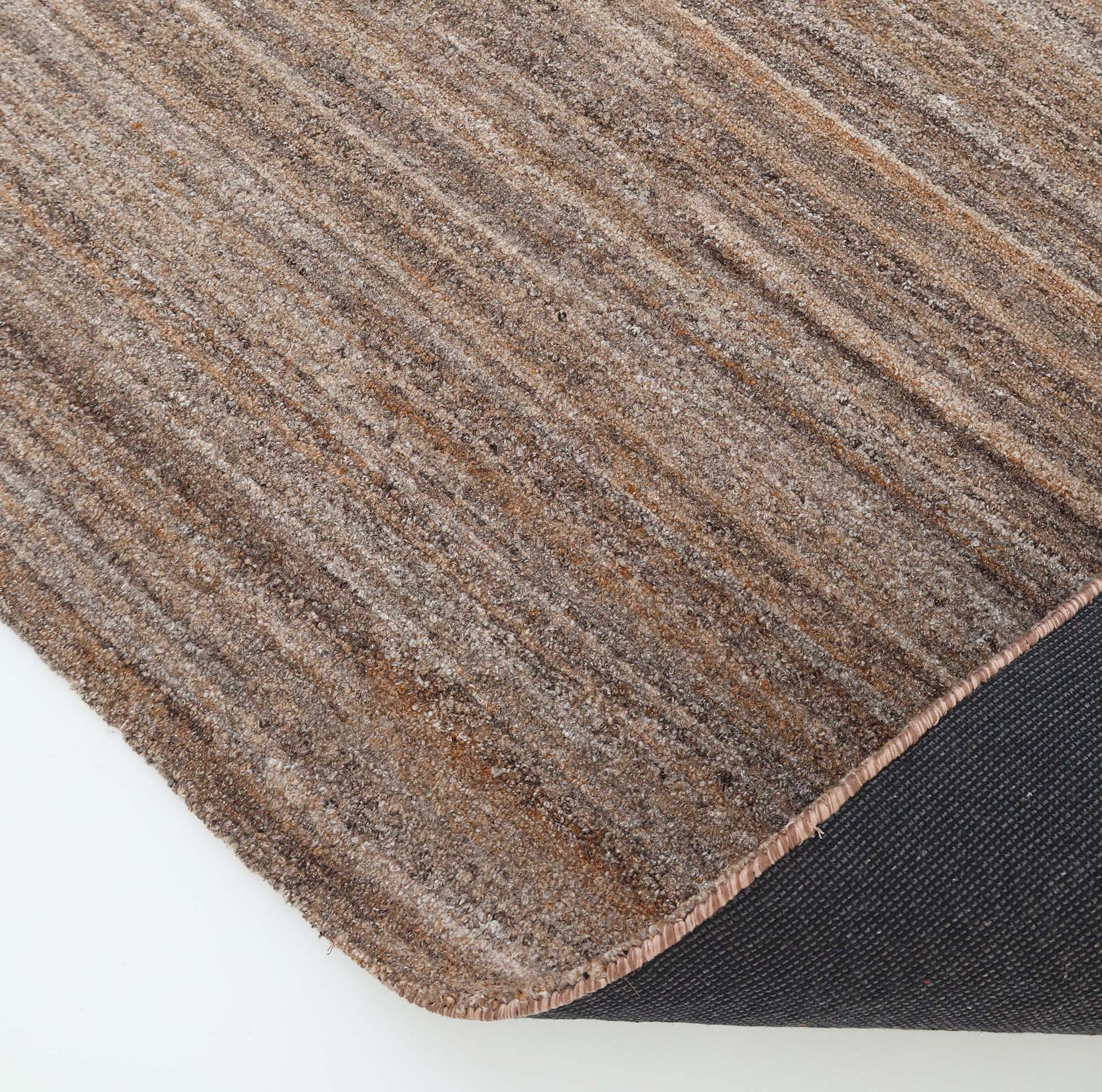 Close-up of the RAMSHA HOME Handmade Earth Strata Wool Rug HTP 29, showcasing its brown stripes and textured surface. A corner is flipped to reveal the black, non-slip backing against a white background.