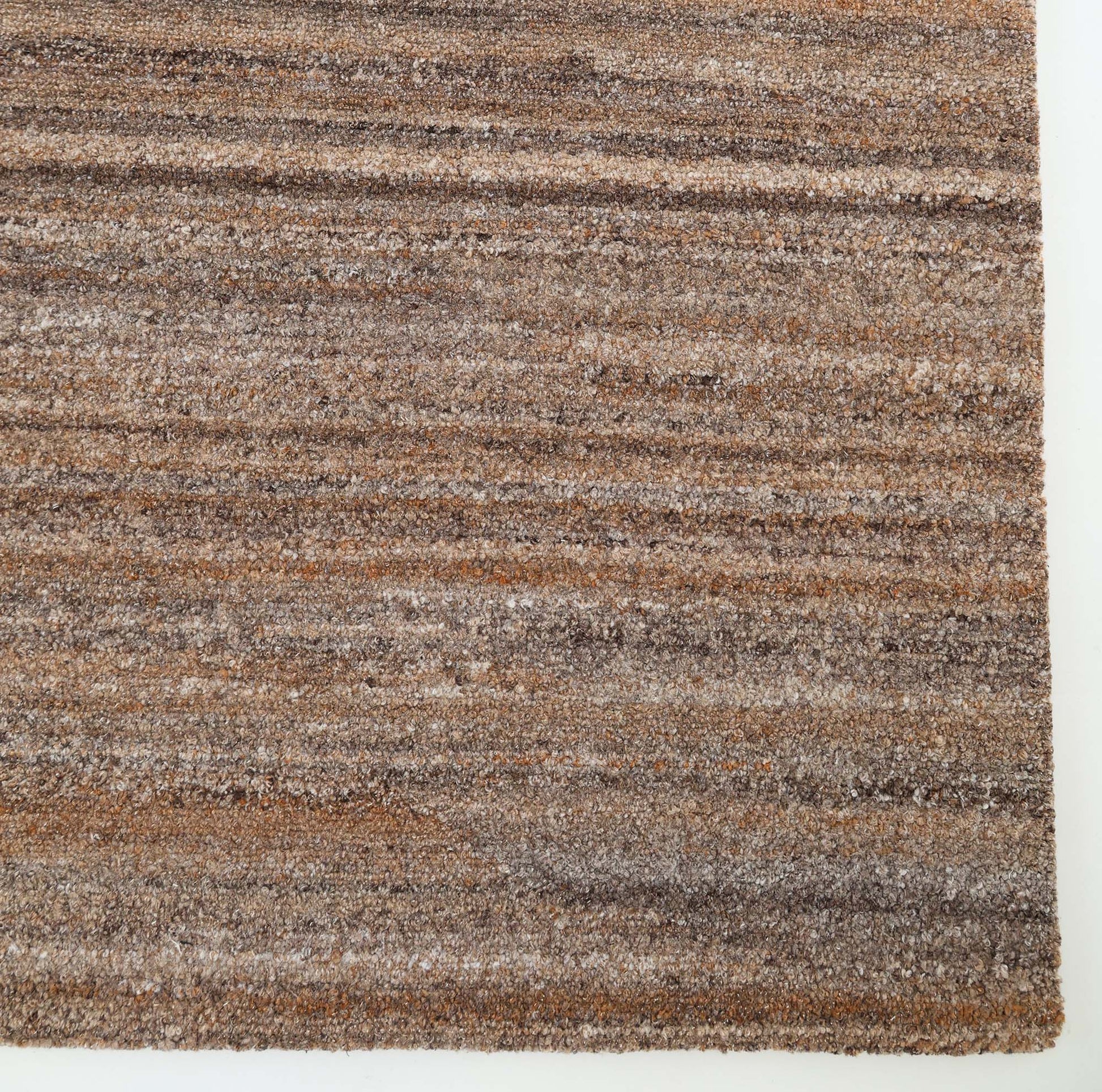 Close-up of the RAMSHA HOME Handmade Earth Strata Wool Rug HTP 29, featuring textured horizontal brown and tan stripes in natural fibers, displayed on a light floor.