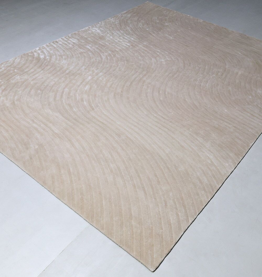 The Off White Handmade Rug - HTV 14 by RAMSHA HOME, a large rectangular modern rug with a subtle wavy texture, is placed on a light-colored floor in a minimalistic setting.