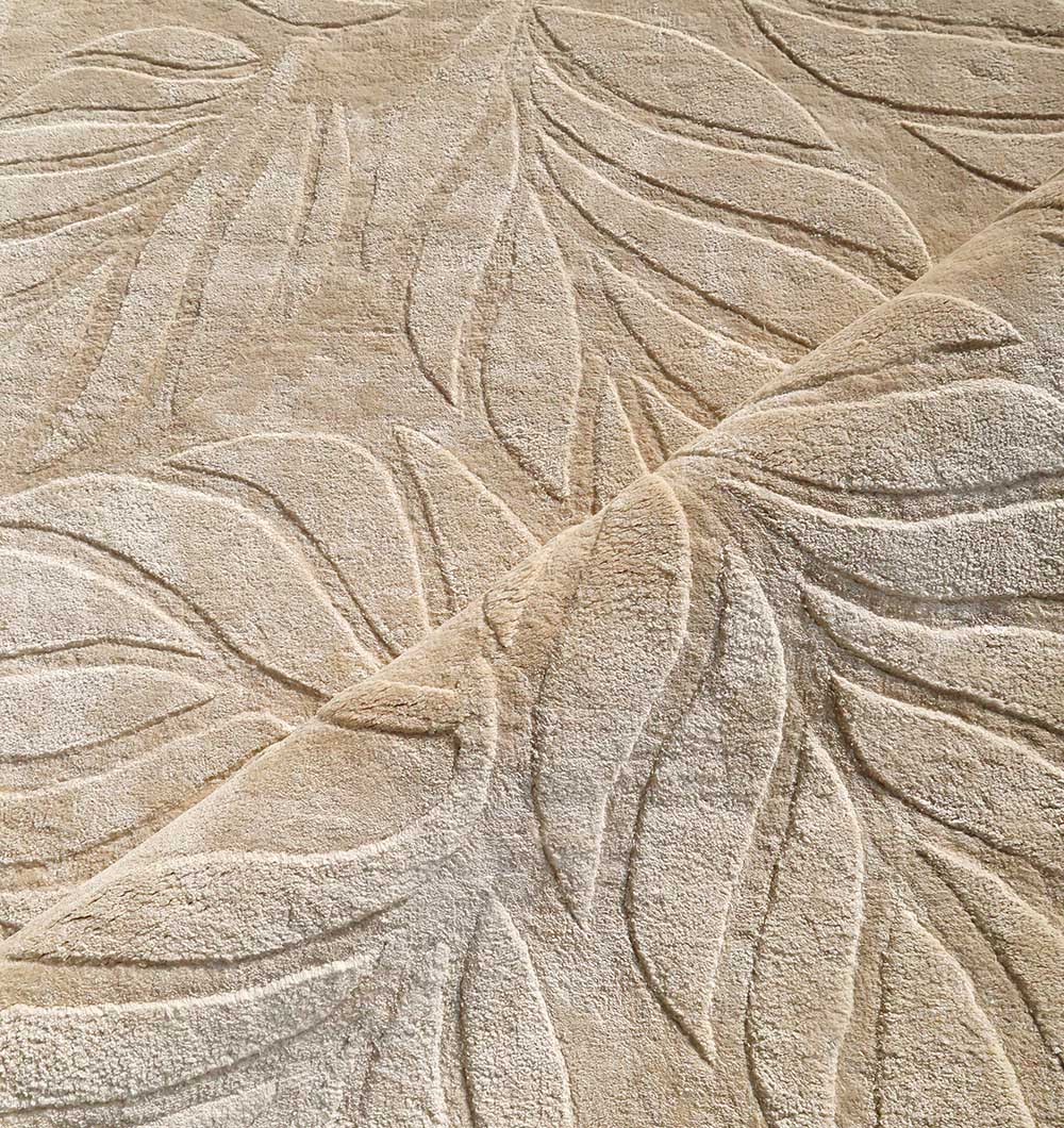 Close-up of the RAMSHA HOME Beige Color Indoor Handmade Area Rug - HTV 15, showing its raised textured leaf pattern and impressive hand-tufted thickness with part of the rug folded over to reveal its inviting softness.