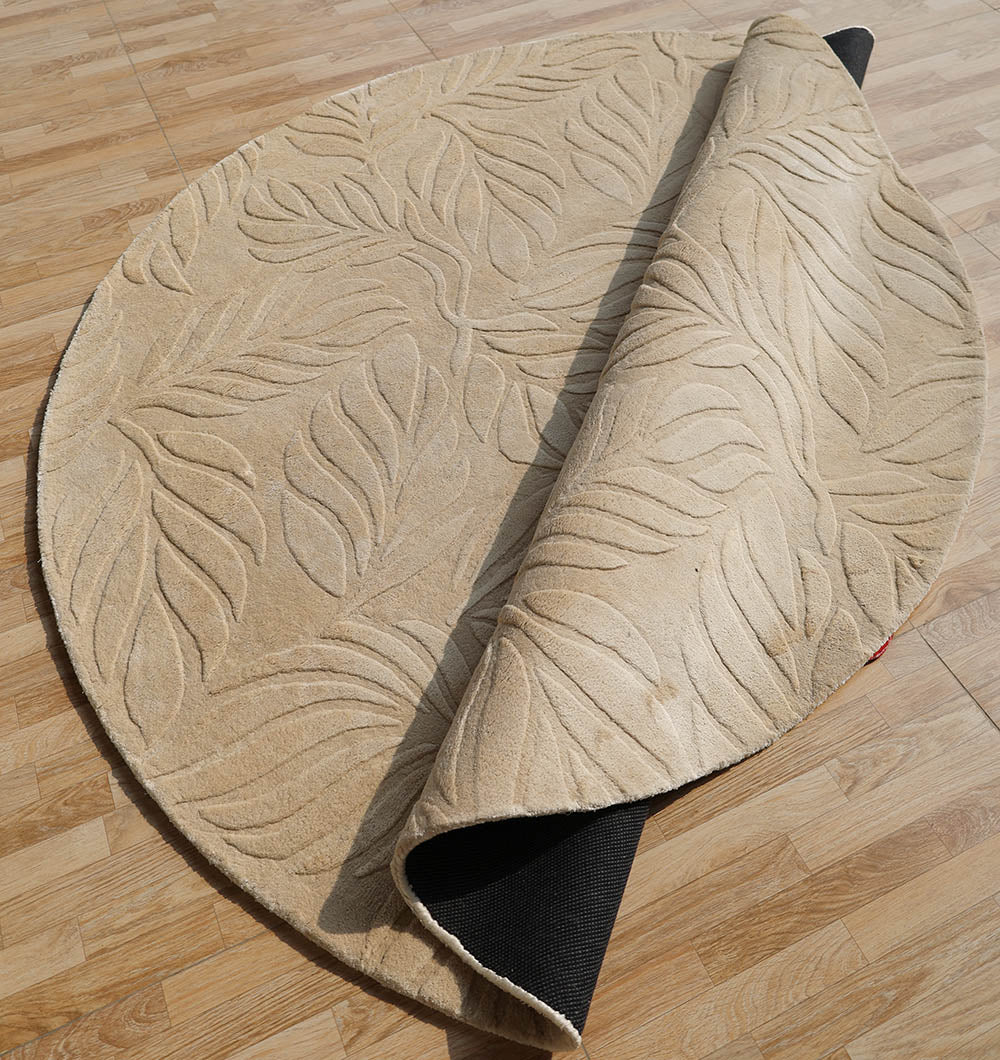 The RAMSHA HOME Beige Color Indoor Handmade Area Rug - HTV 15 features a raised leaf pattern and a black underside, shown partially rolled up on a light wood floor.