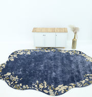 The RAMSHA HOME Navy Blue Viscose Shaped Handmade Carpet 200x300 (HTV-23), featuring beige abstract patterns, lies on a white floor in front of a small white cabinet with a wooden top and a tall vase with pampas grass beside it.