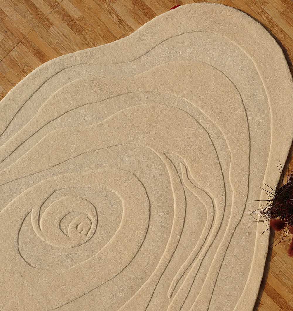 A RAMSHA HOME Natural White Handmade Rug (HTW 100, 200x300 cm) with irregular, raised concentric lines resembling topographic contours lies on a wooden floor. Dark red decorative twigs are partially visible in the corner.