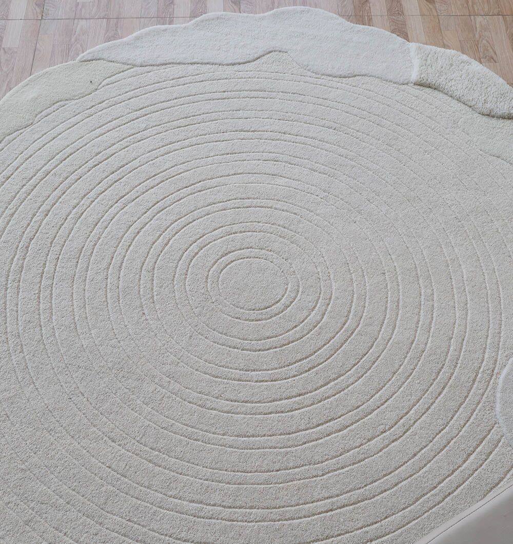 The RAMSHA HOME Multi Color Handmade Area Rug - HTW 109 (183x200 Cm) features concentric circle patterns and a scalloped edge, bringing a modern decorative accent to light wooden floors.