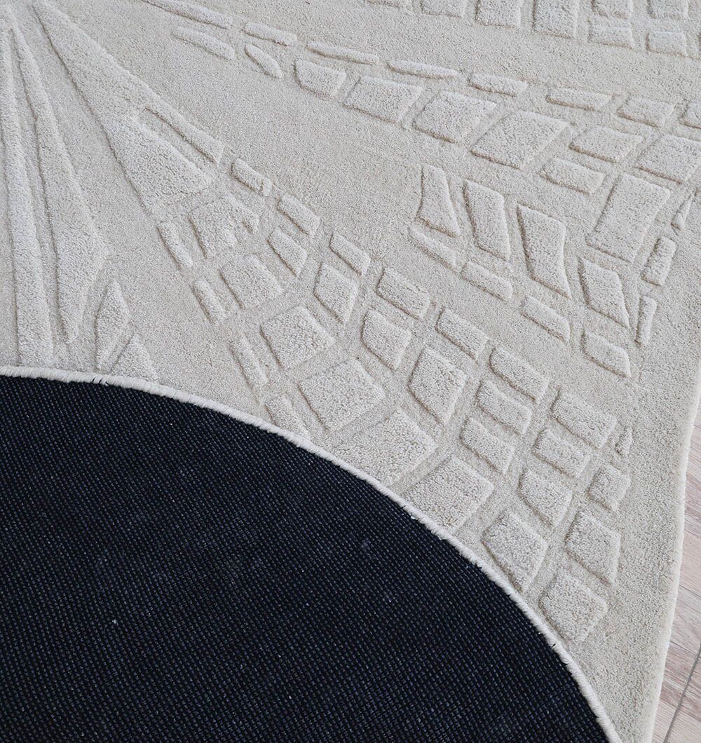 A close-up of the RAMSHA HOME Handmade Area Rug - HTW 112 (200x300 cm) in ivory-beige, featuring a geometric hand-tufted design and a flipped corner showing its black non-slip backing.