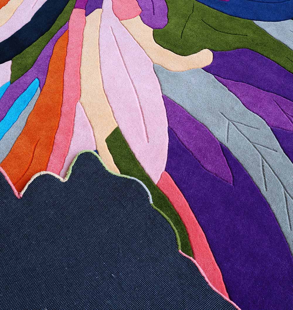 A close-up of the RAMSHA HOME Multi Color Handmade Area Rug - HTW 113 (200x300 cm) showing abstract feather or leaf shapes, hand-tufted with a dark navy base and a vibrant border.