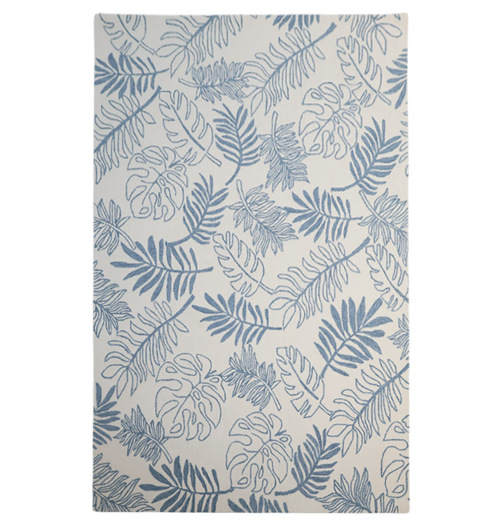 The RAMSHA HOME Home Decor Handmade Carpet – HTW-119 is a rectangular blue botanical wool rug with a white background, featuring hand-tufted construction and a stylish pattern of monstera and palm leaves.