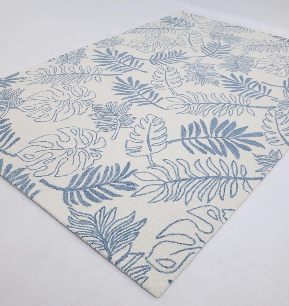 The RAMSHA HOME Handmade Carpet – HTW-119 is a rectangular blue botanical rug featuring blue tropical leaf patterns on a cream background, displayed on a white surface.