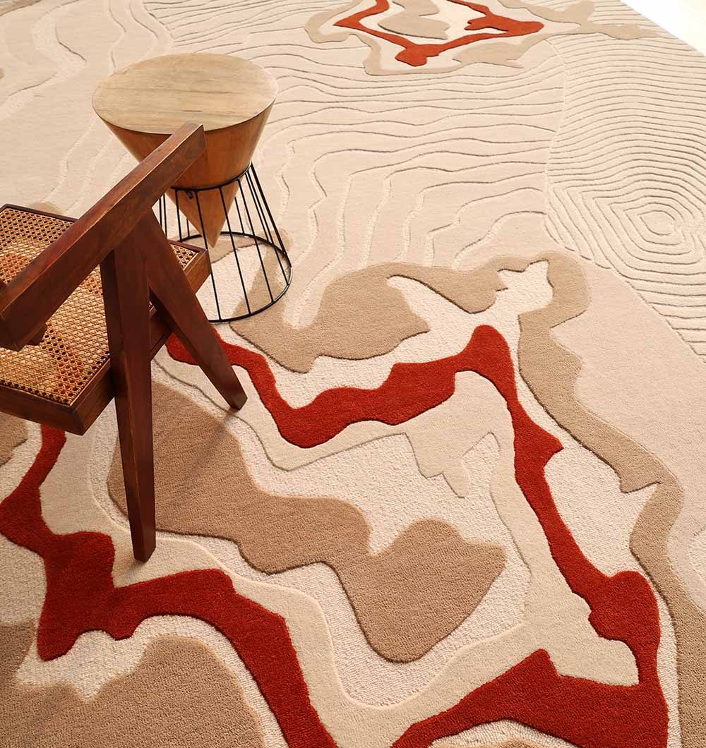 A modern room showcases the RAMSHA HOME Modern Handmade Carpet 300x400 Multi – HTW-120 in a topographic beige, tan, and red pattern, paired with a wooden woven-seat chair and a small round wire-base side table.