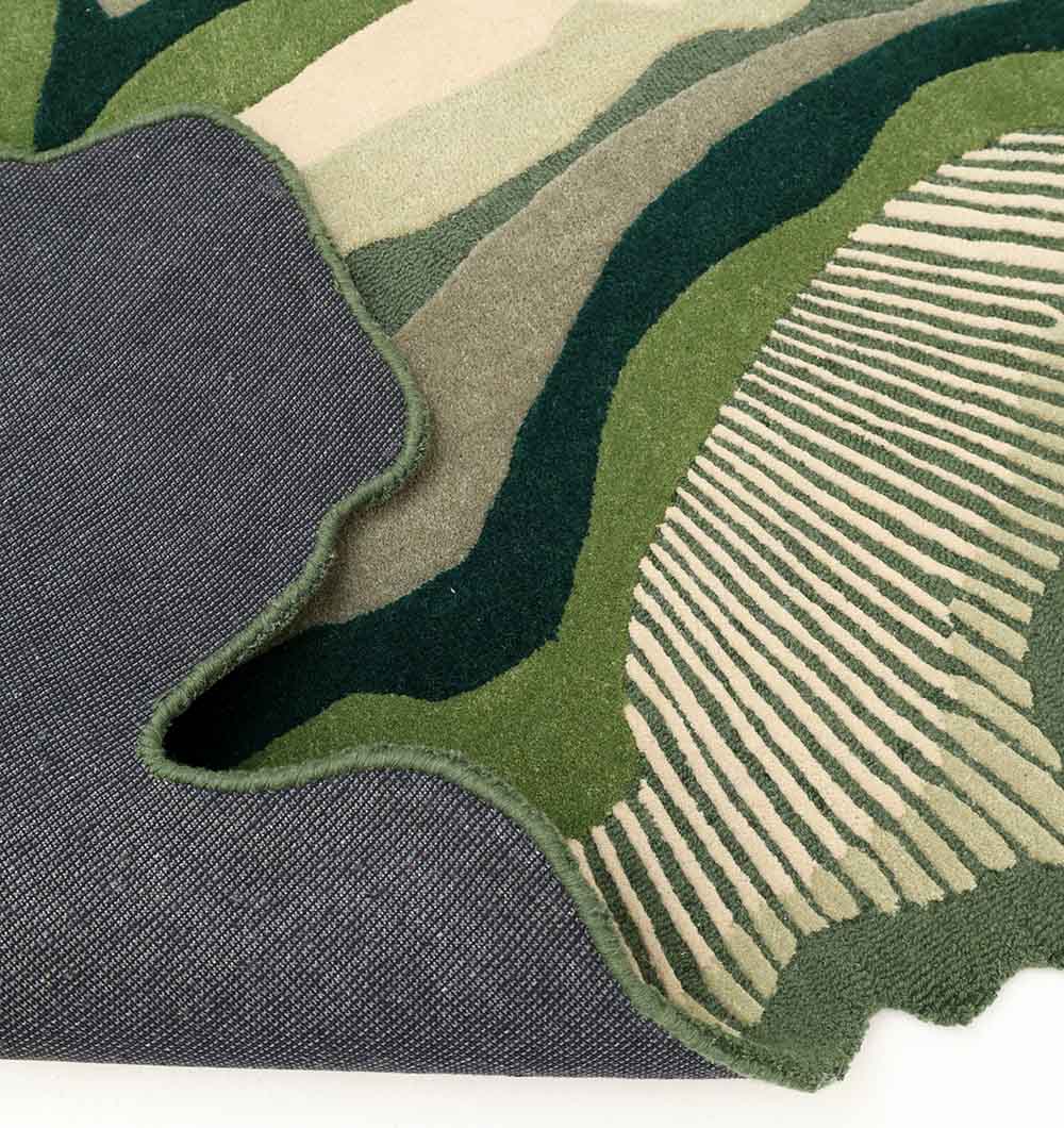 A close-up of the RAMSHA HOME Handmade Organic Green Shaped Rug - HTW 123 (200cm) shows its abstract cream and dark green wavy patterns and the textured underside, highlighting its hand-tufted craftsmanship.
