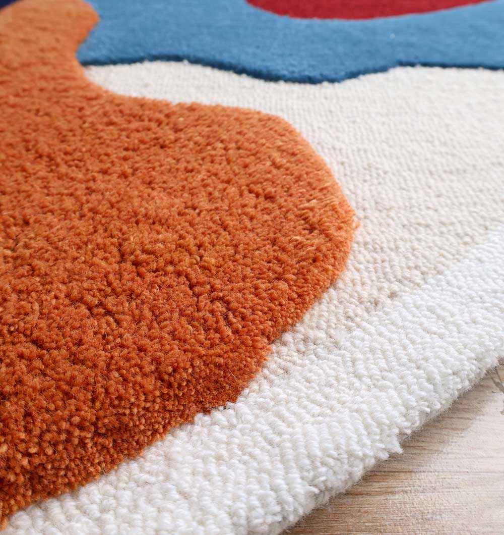 A close-up of the RAMSHA HOME Handmade Wool & Cotton Abstract Round Area Rug HTW 125 (200cm), featuring soft, plush hand-tufted fibers in orange, cream, and blue on a wooden floor.
