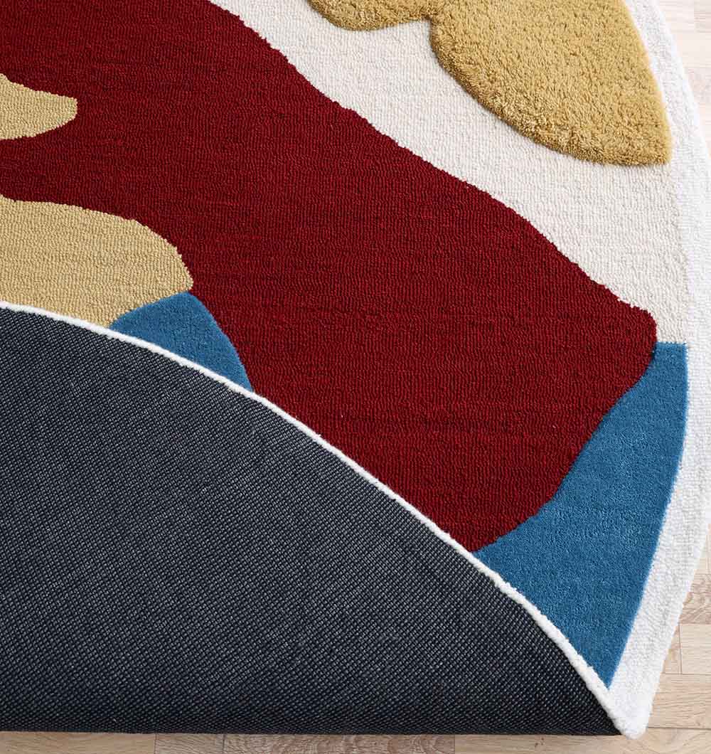 The RAMSHA HOME Handmade Wool & Cotton Abstract Round Area Rug HTW 125 (200cm) features vibrant red, mustard, white, and blue curved shapes with a textured dark gray backing, adding modern style to your space.