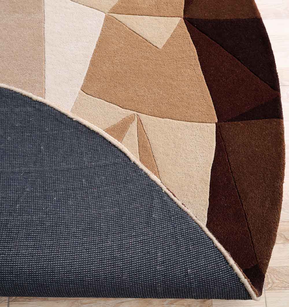 The RAMSHA HOME Handmade Multicolor Geometric Pattern Round Area Rug HTW 129 (200cm) is partially lifted to show a non-slip gray rug pad underneath on a light wood floor.