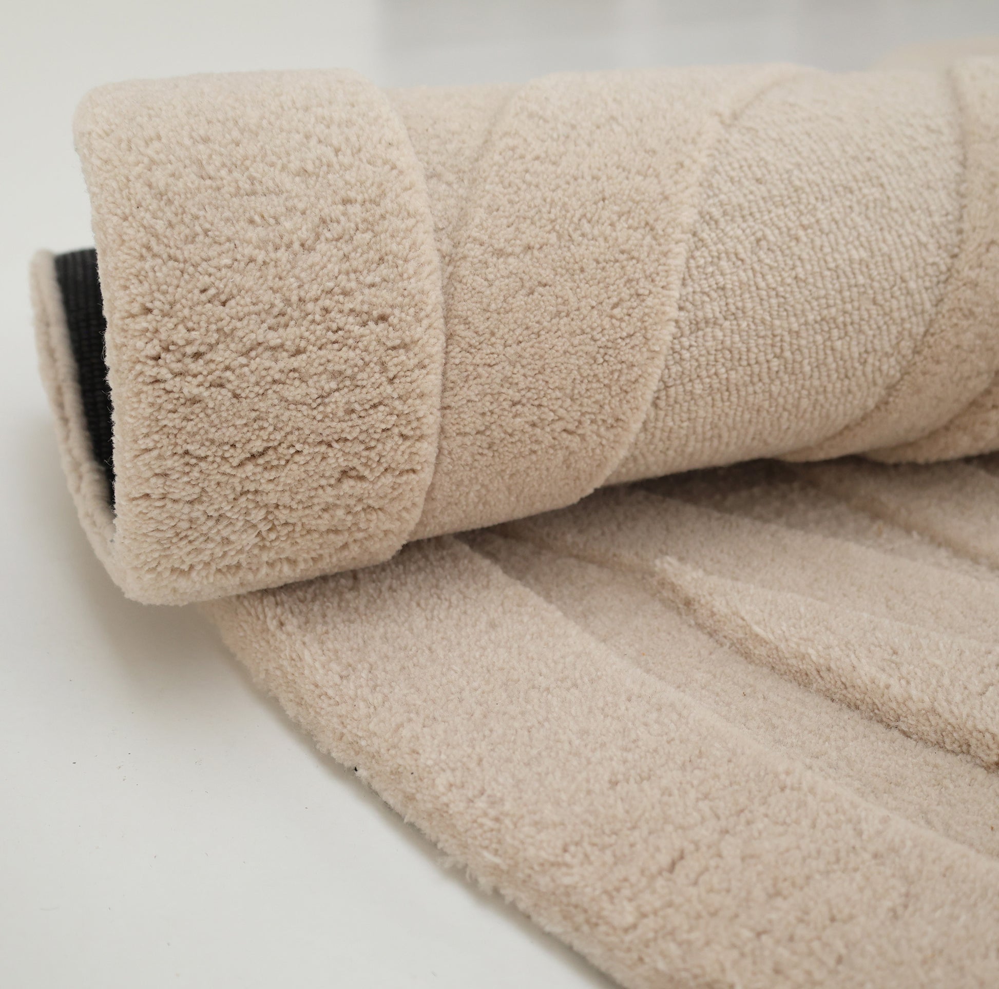 A close-up of the RAMSHA HOME Contemporary Flow Area Handmade Rug HTW-146, featuring a soft, plush surface and subtle topographic pattern, rolled up on a white background.