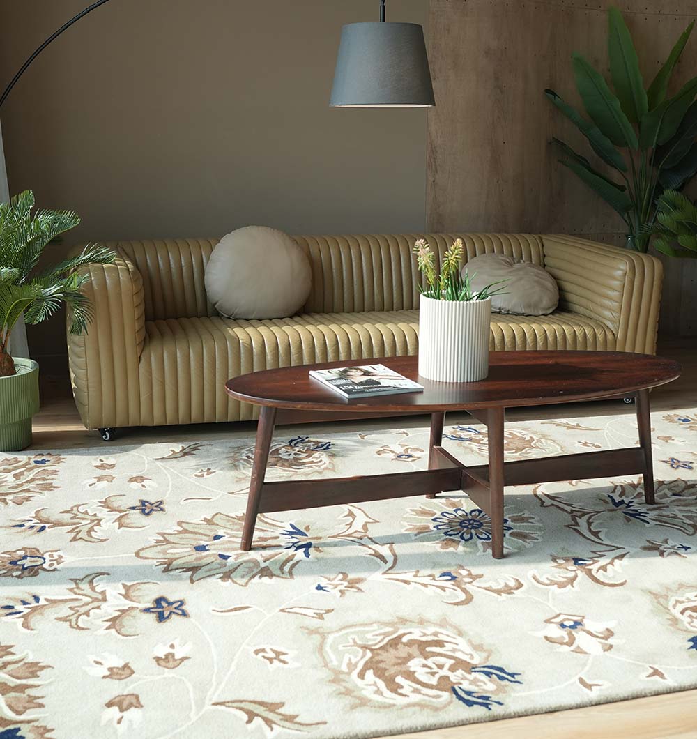 A modern living room featuring a tan ribbed sofa, round cushions, wooden coffee table with plant and magazine, potted plants, gray hanging lamp, and the RAMSHA HOME Handmade Carpet HTW-14 for classic Persian elegance.