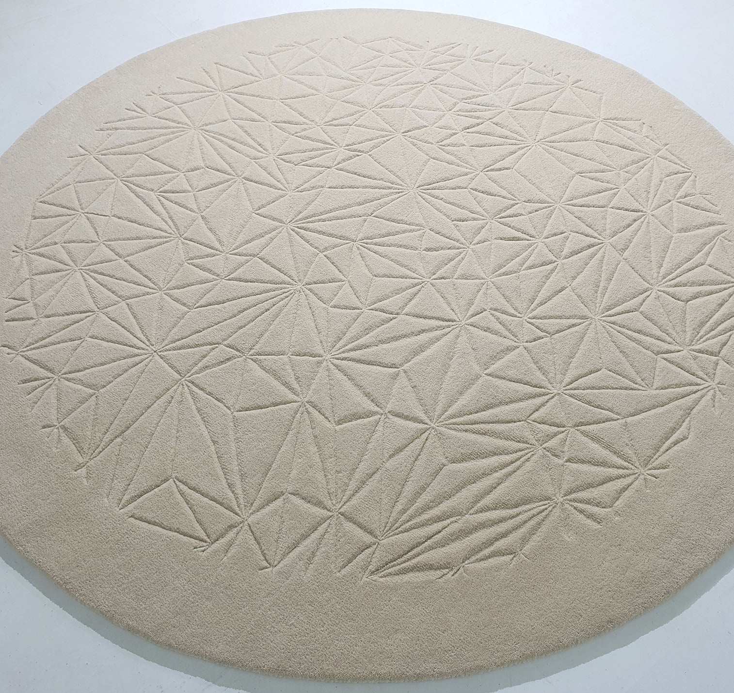 The RAMSHA HOME Luxury Home Decor Handmade Carpet – HTW-65 is a round, hand-tufted beige rug with an embossed geometric pattern, bringing textured, modern elegance to any space.