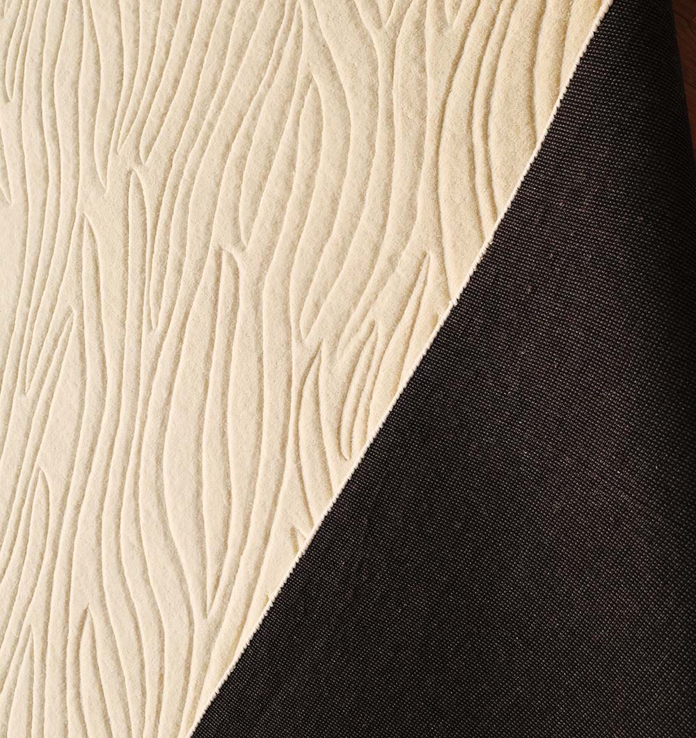 A close-up shows the RAMSHA HOME Natural White Color Handmade Area Rug - HTW-89 (300x400 CM), featuring a raised, wavy cream wool pattern, placed diagonally beside a solid black textured fabric.