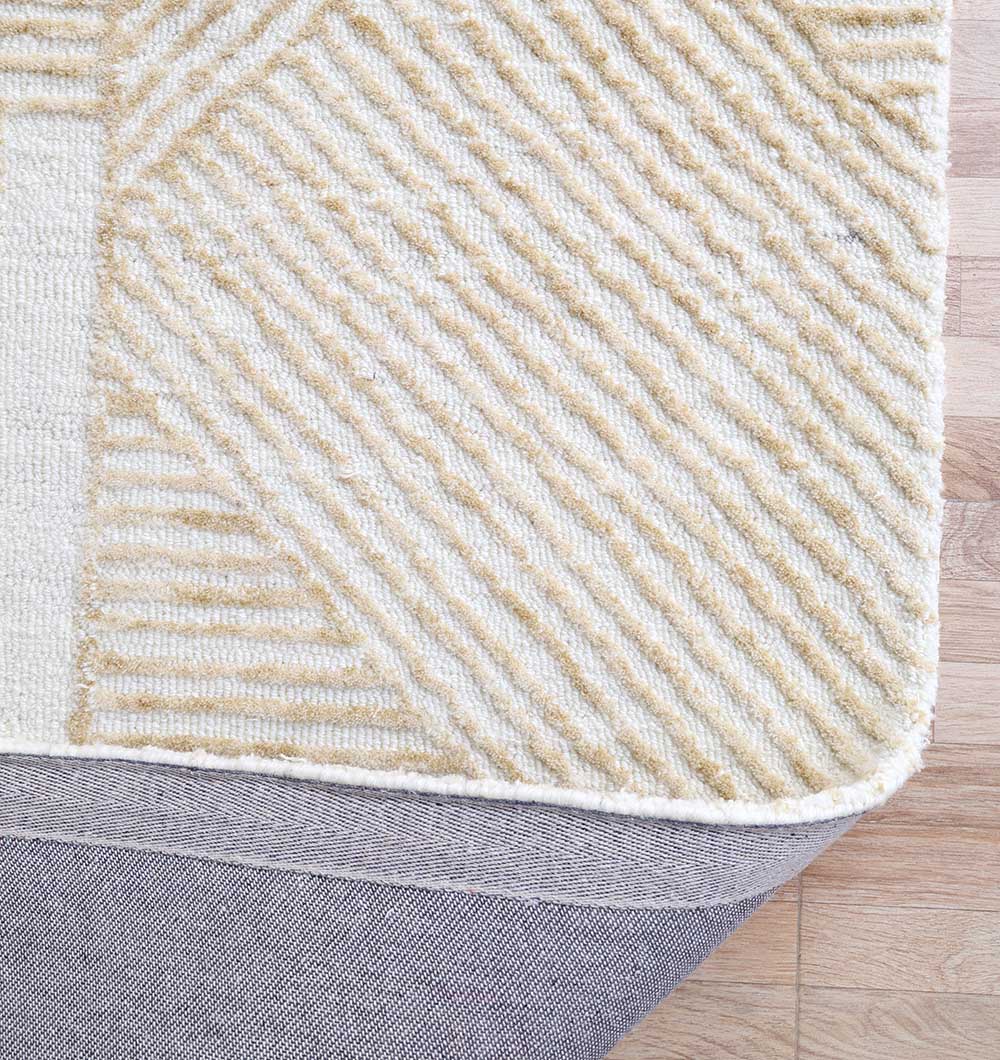 A close-up of the RAMSHA HOME Multi Color Handmade Area Rug - HTW-91 (200X300 CM), featuring beige and cream diagonal stripes, slightly lifted at the corner to show a gray rug pad on a light wood floor.