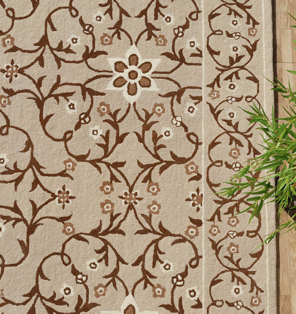 The Exquisite Multi Color Decor Handmade Rug - HTW 99 (300x400 CM) by RAMSHA HOME features ornate brown floral and vine motifs on beige, bordered on one side with green bamboo leaves near a wooden surface for added elegance.